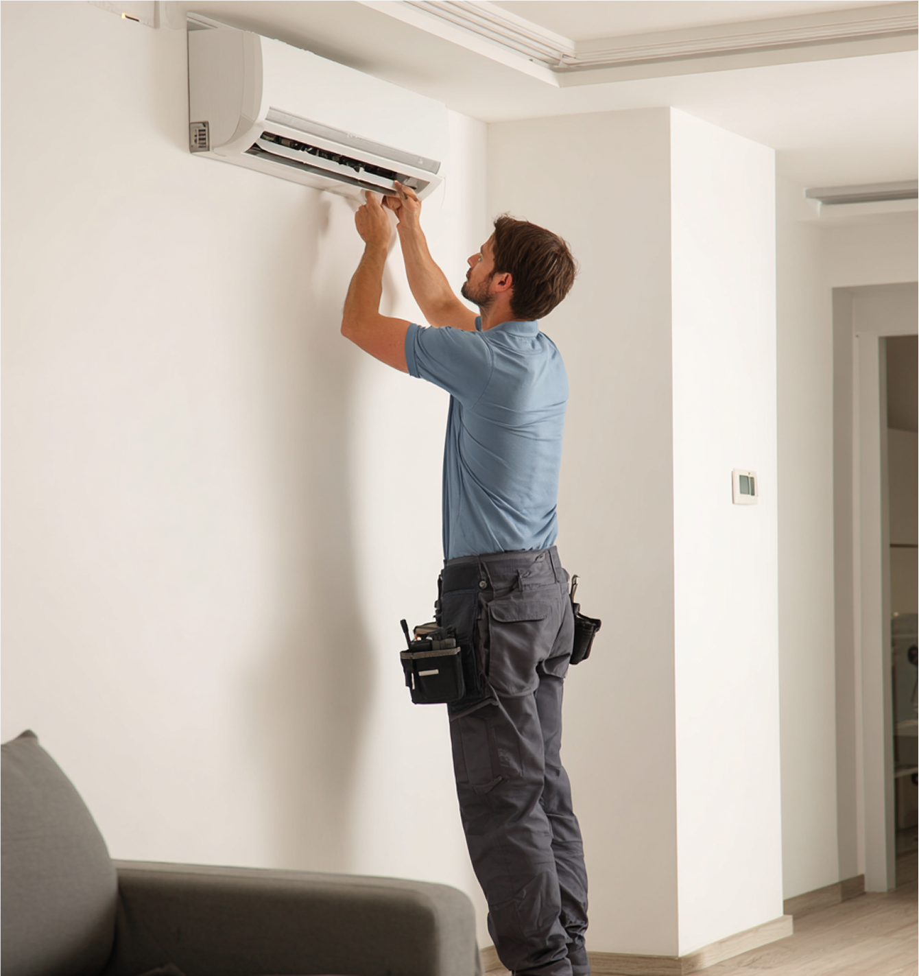 Man installing or repairing an AC unit on a white wall.