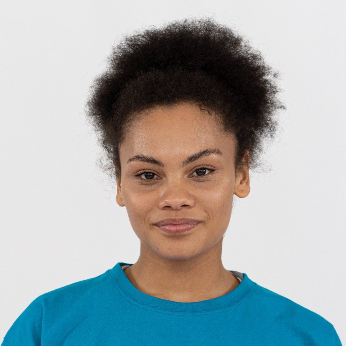 Woman in a blue shirt smiling against a plain white background