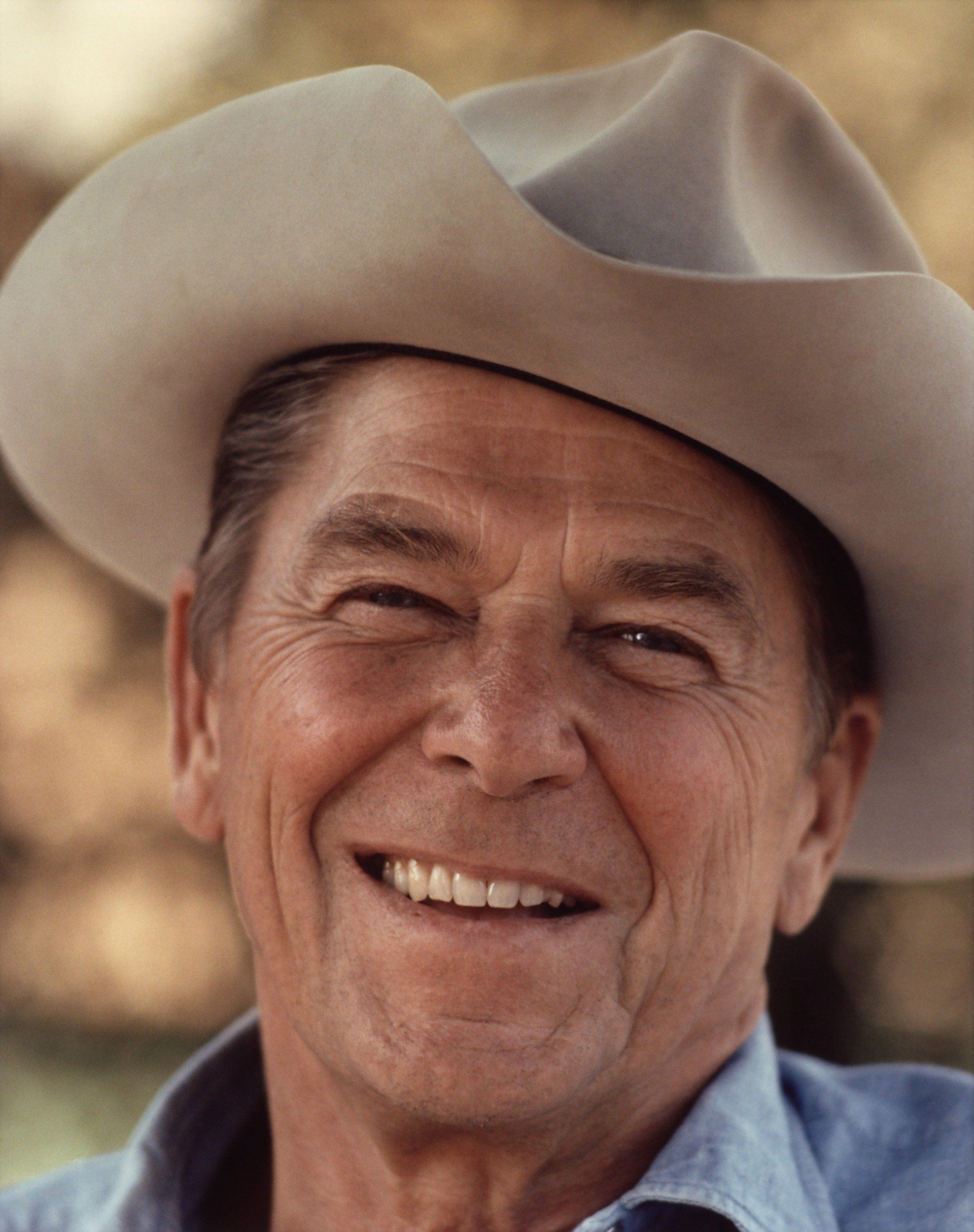 A man wearing a cowboy hat is smiling for the camera