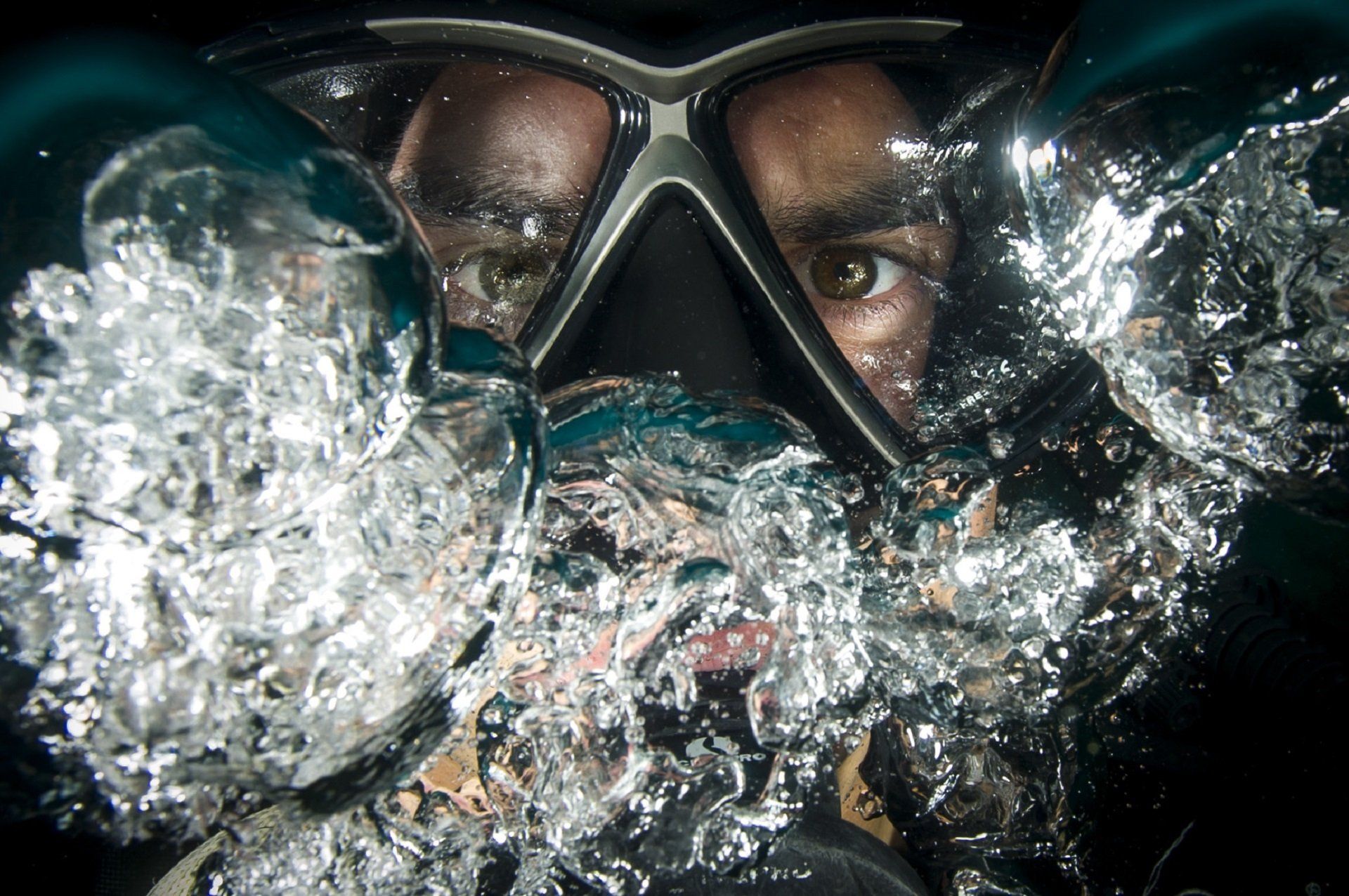 A man wearing a mask and goggles is swimming in the water.