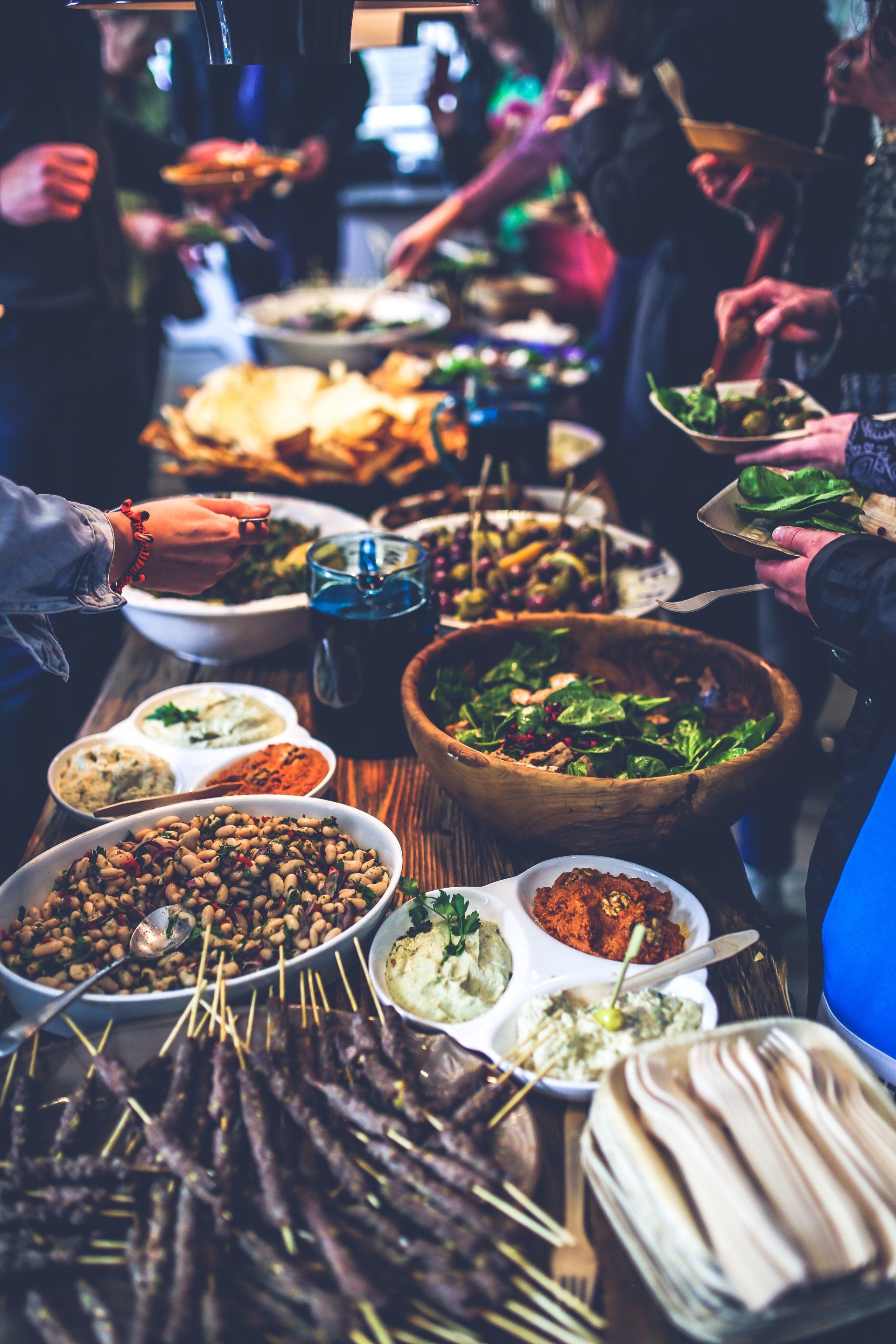A group of people are standing around a table eating food.