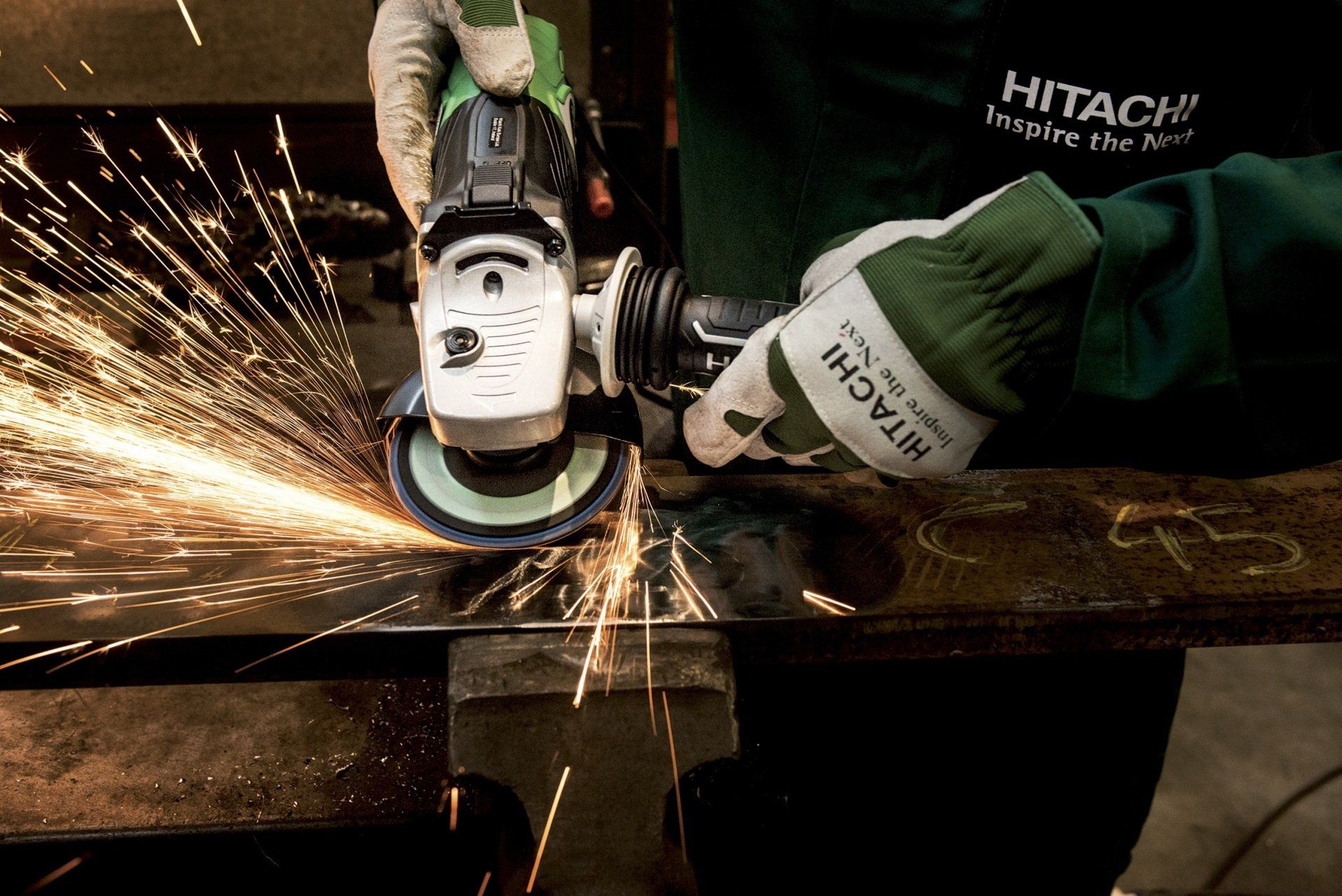 A person wearing hitachi gloves is grinding a piece of metal