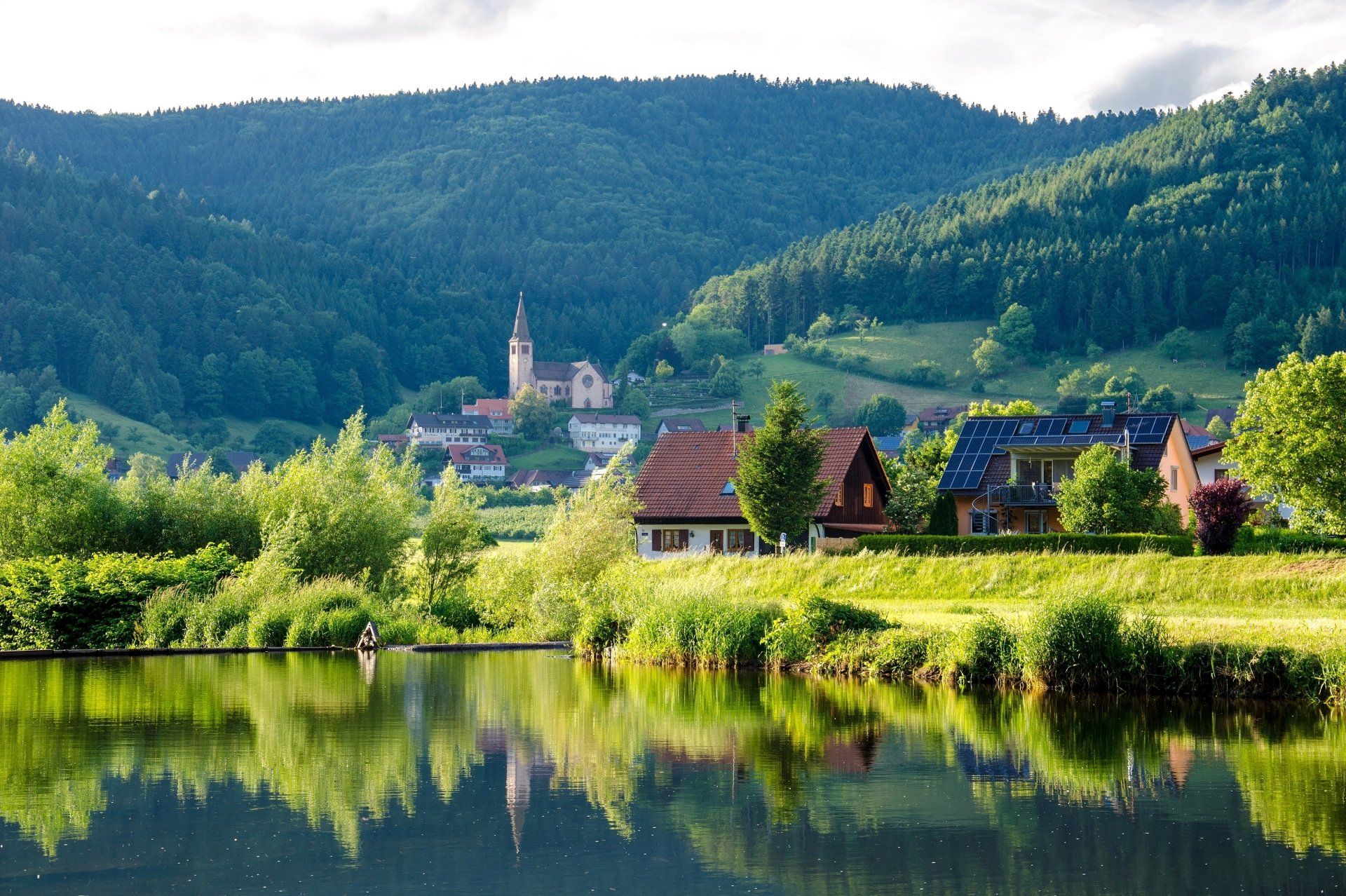 A lake with mountains in the background and houses in the foreground
