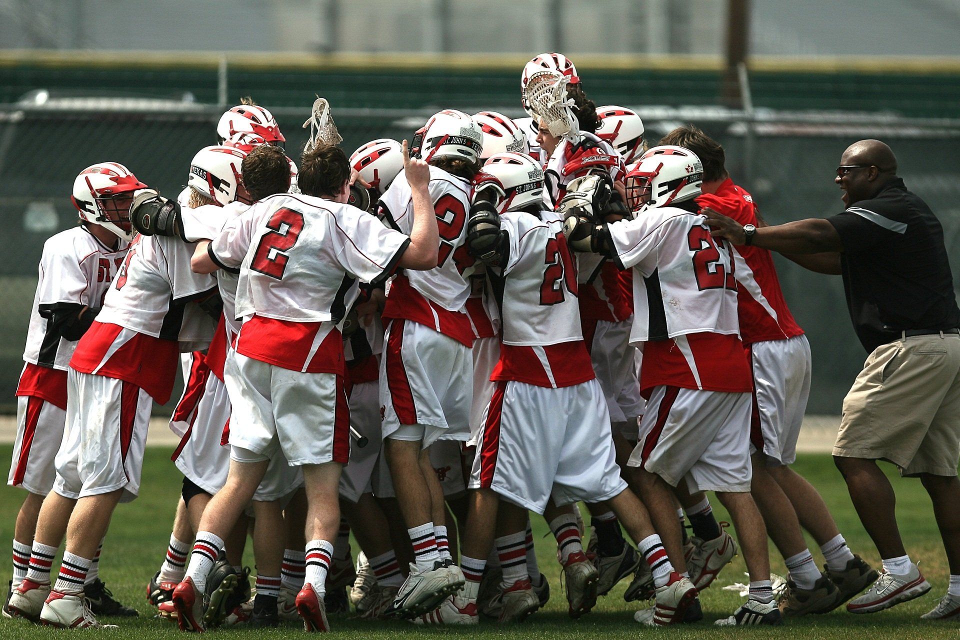 A group of lacrosse players are huddled together on the field