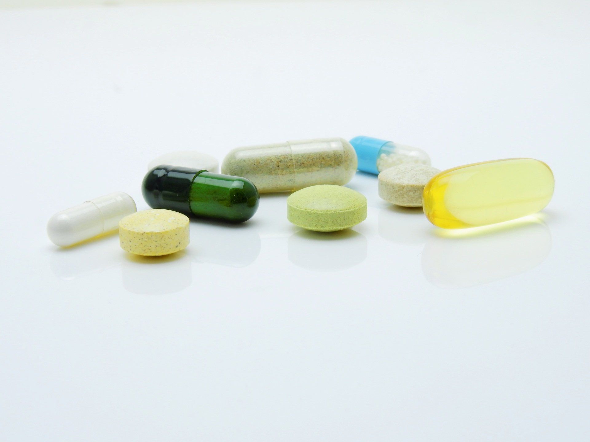 a variety of pills and capsules are sitting on a white surface .