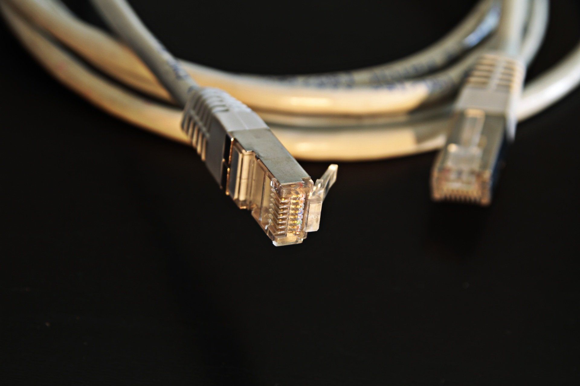 Two ethernet cables are connected to each other on a black surface.