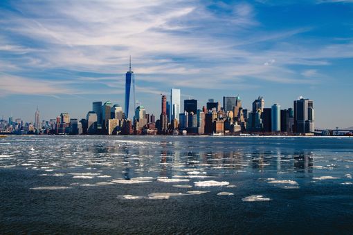 New York City skyline on a sunny day reflected in icy water.