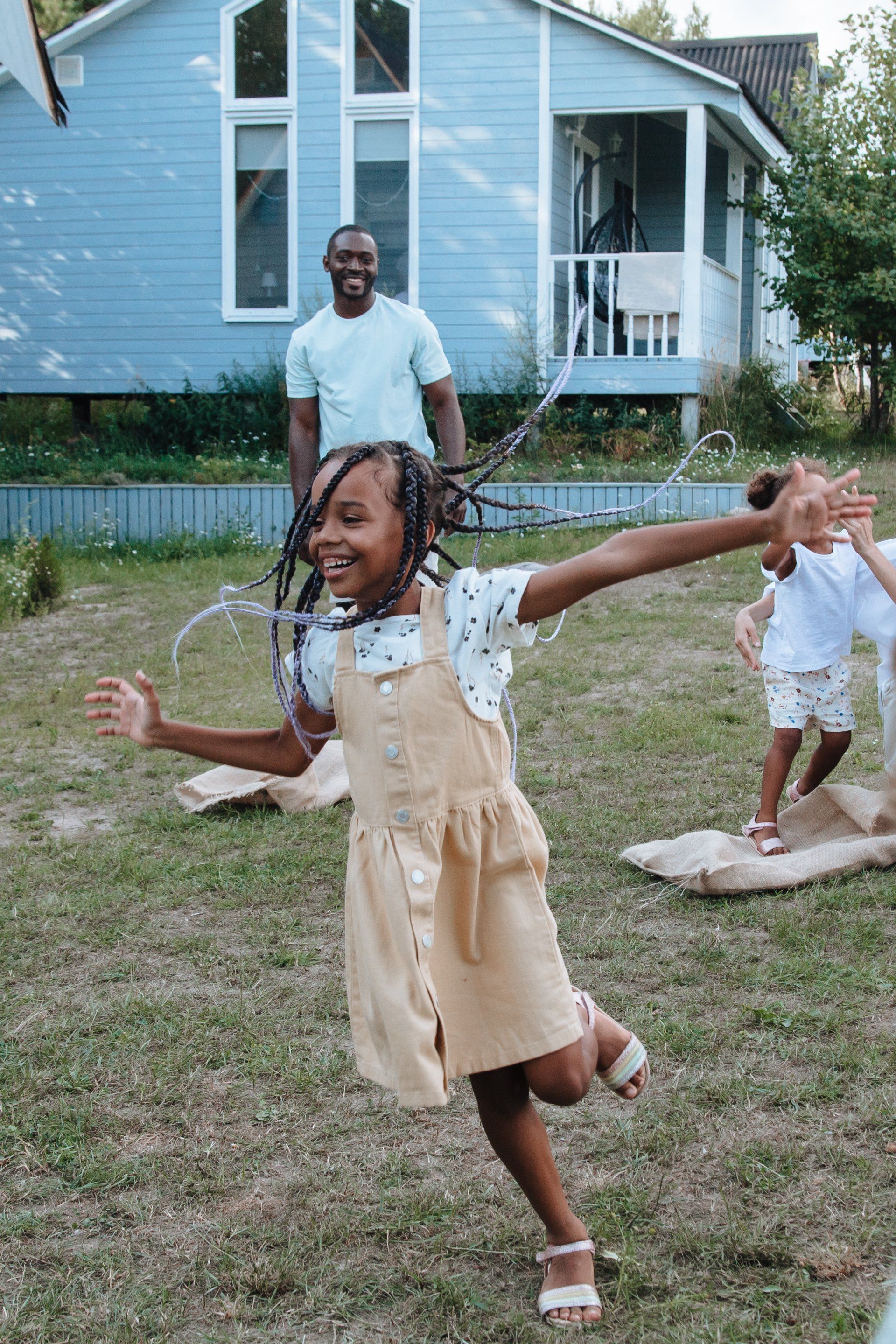 A little girl is running in a field with her arms outstretched.