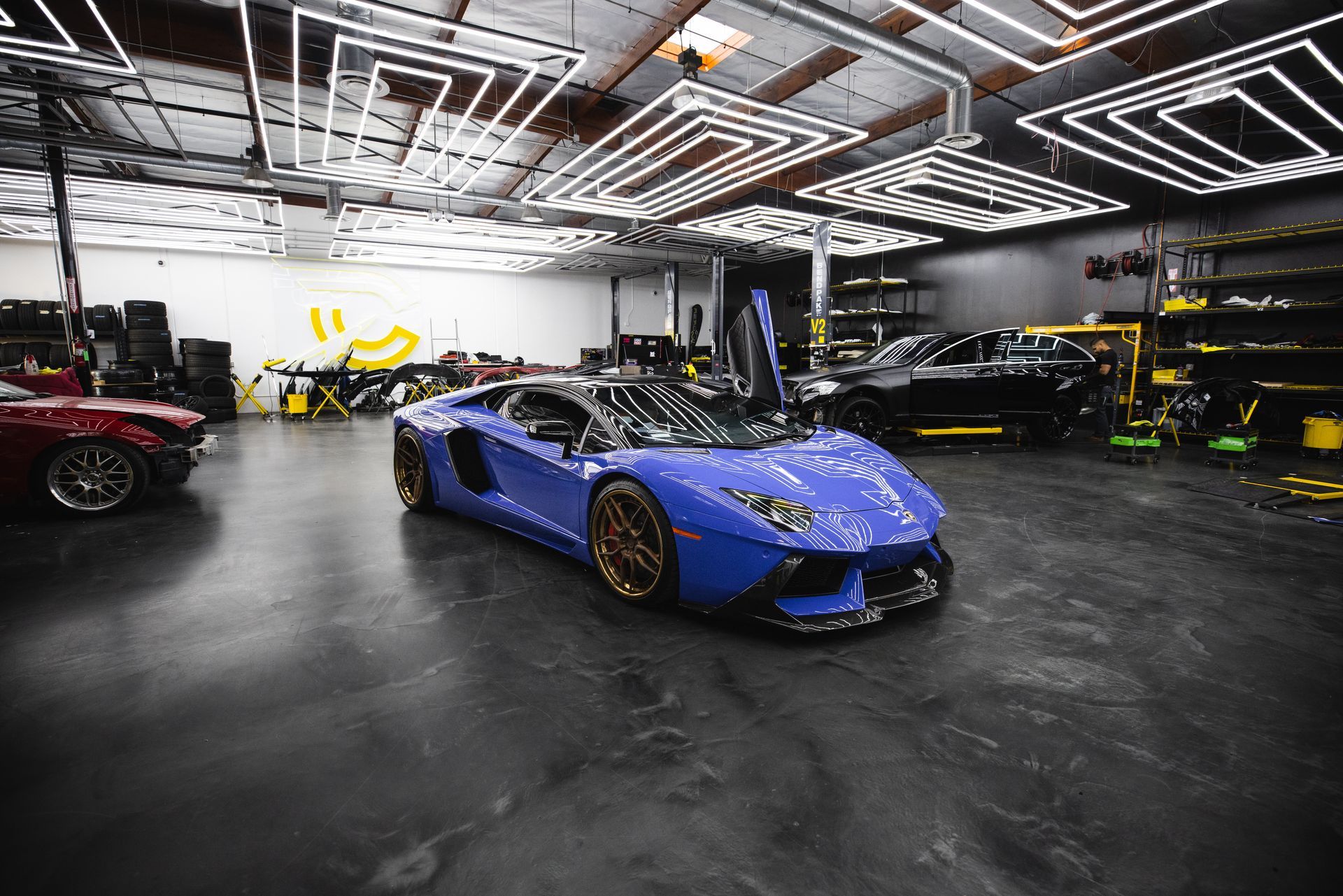 A blue lamborghini aventador is parked in a garage.