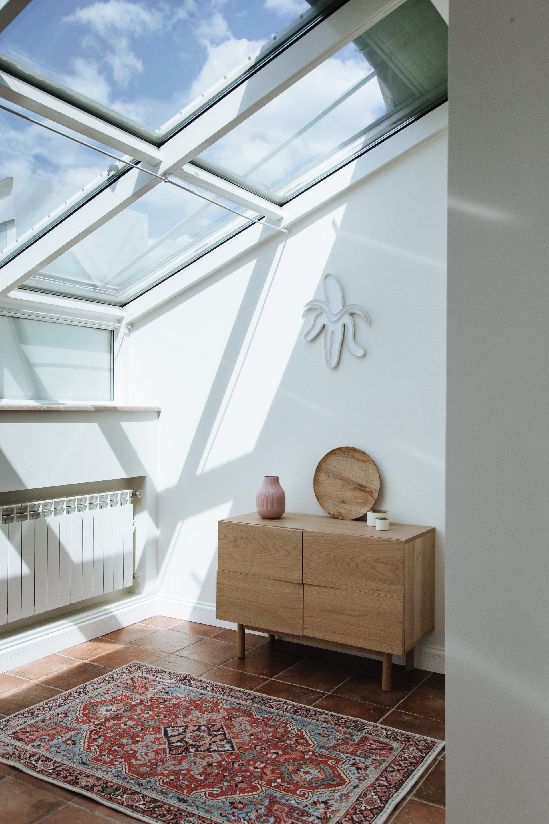 A room with a rug , dresser , and skylight.