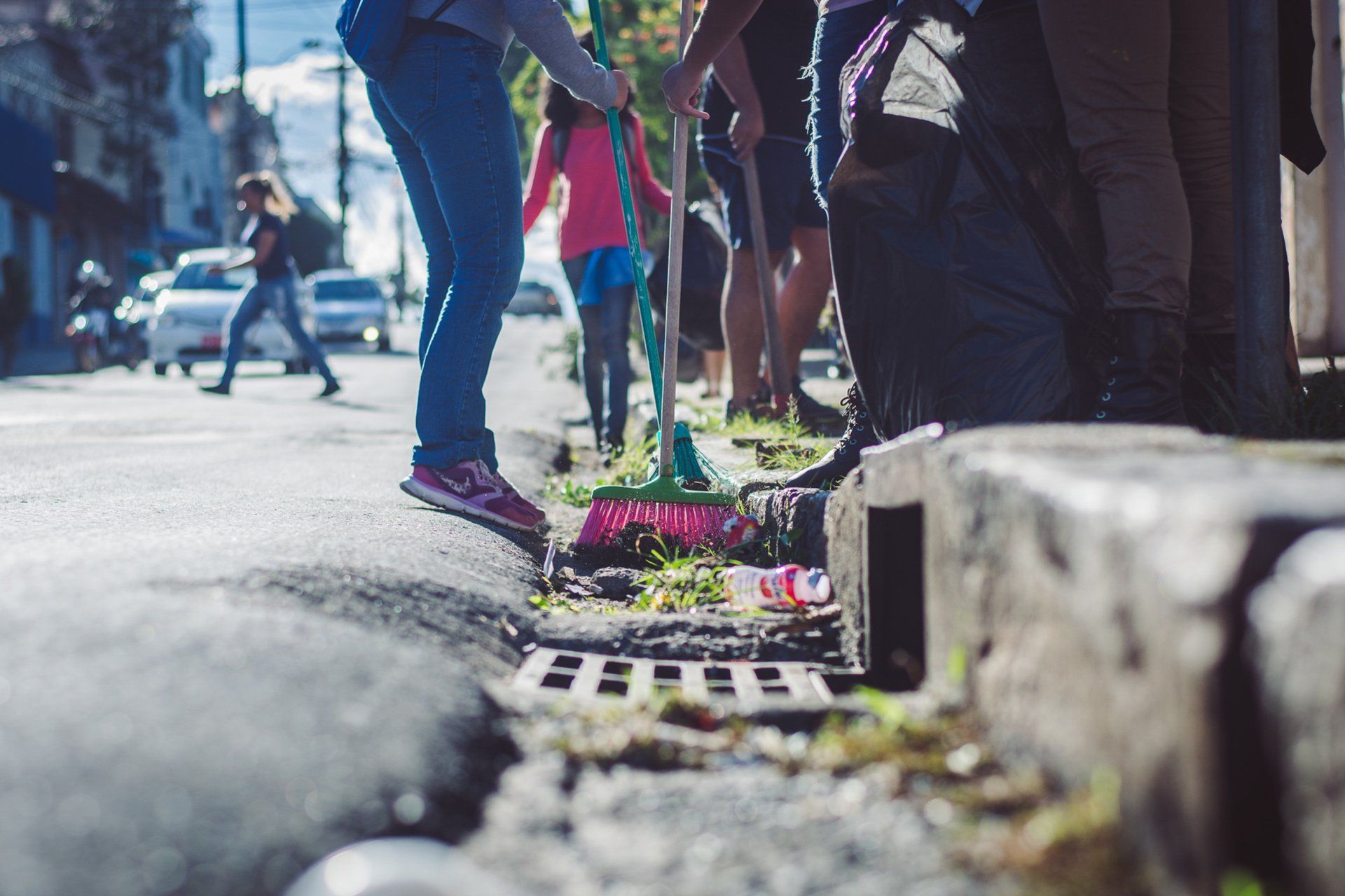 A group of people are cleaning the sidewalk with a broom.