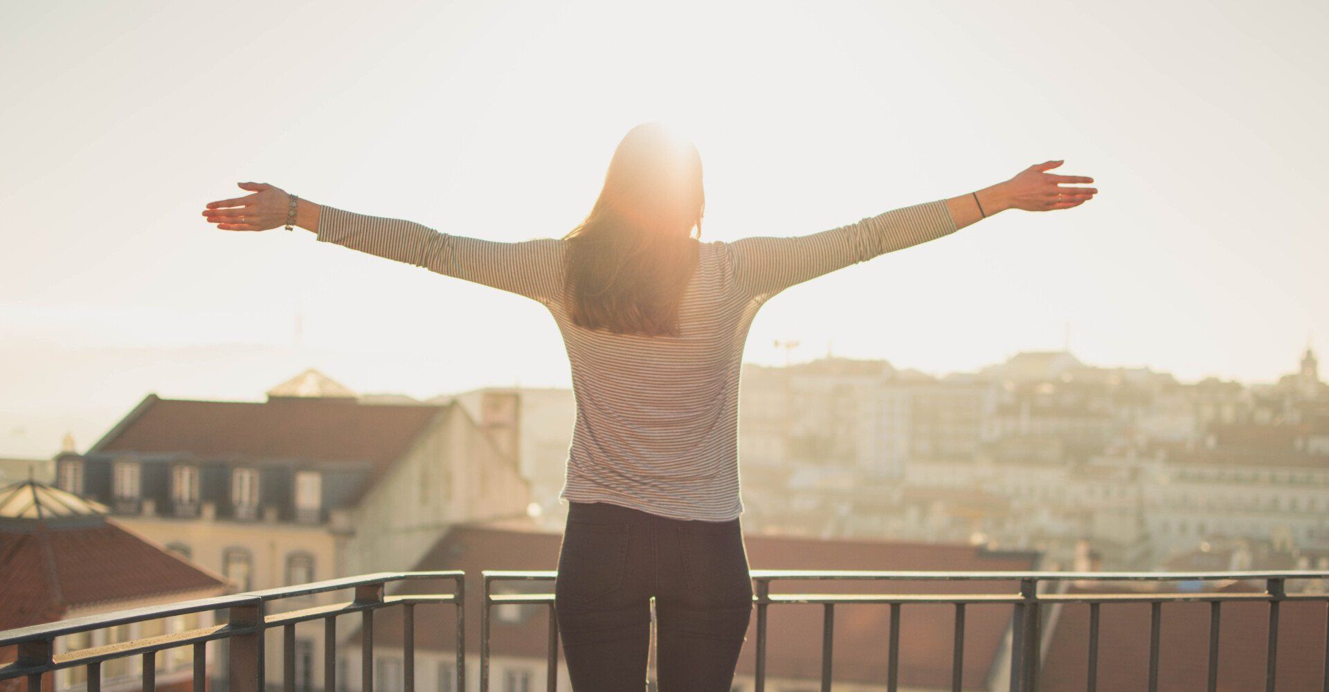 A woman standing with her arms open wide feeling freedom from guilt and shame after catholic counseling in Texas