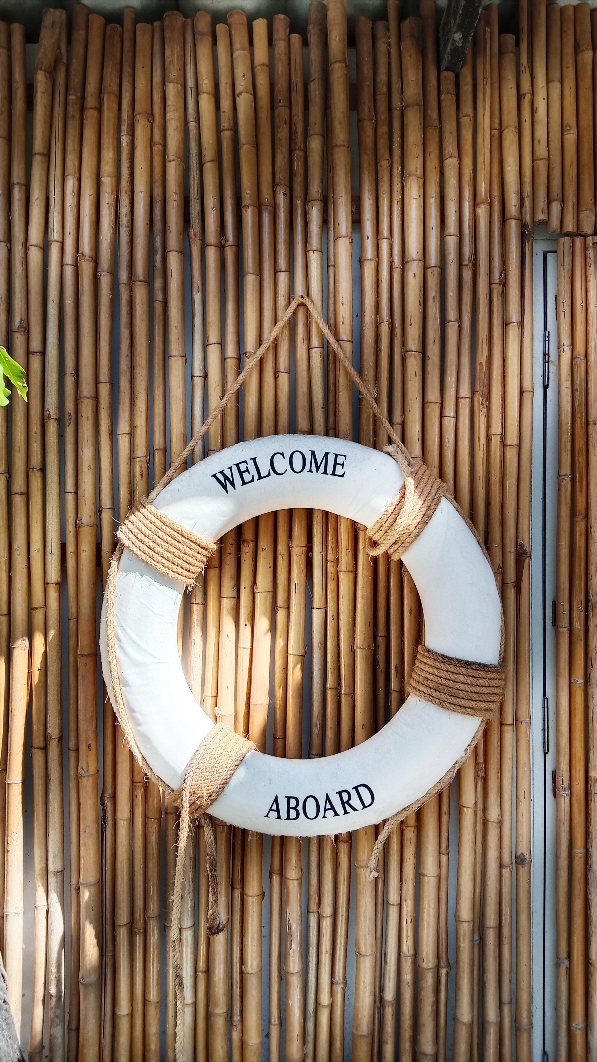 A life preserver is hanging on a bamboo wall.