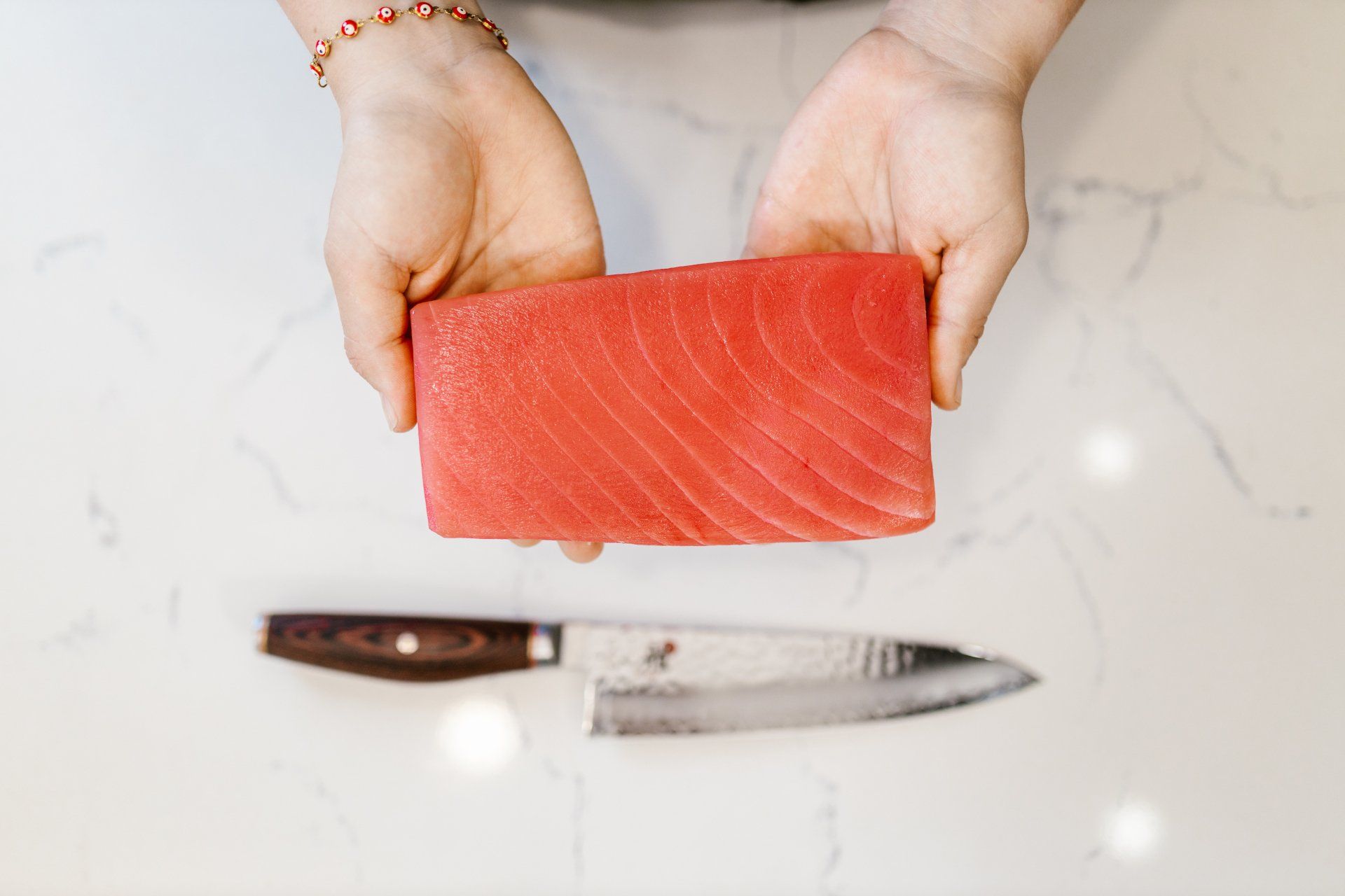 A person is holding a piece of tuna in their hands.