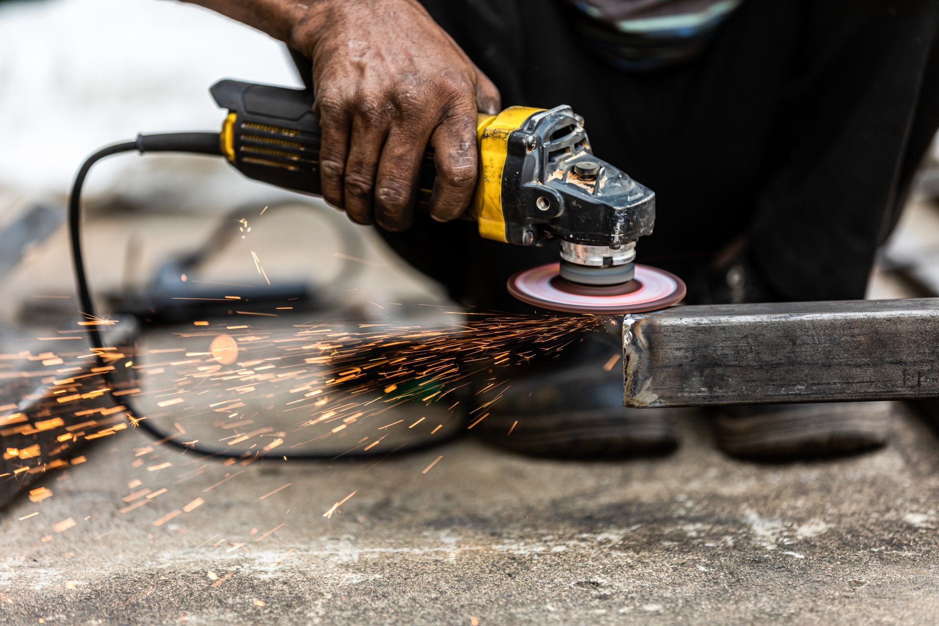 A Man is Grinding a Piece of Metal With a Grinder — NQBC Pty Ltd in Bowen, QLD