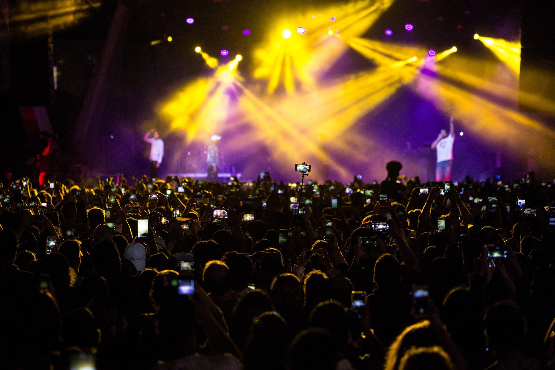 A crowd of people are taking pictures of a concert with their phones.