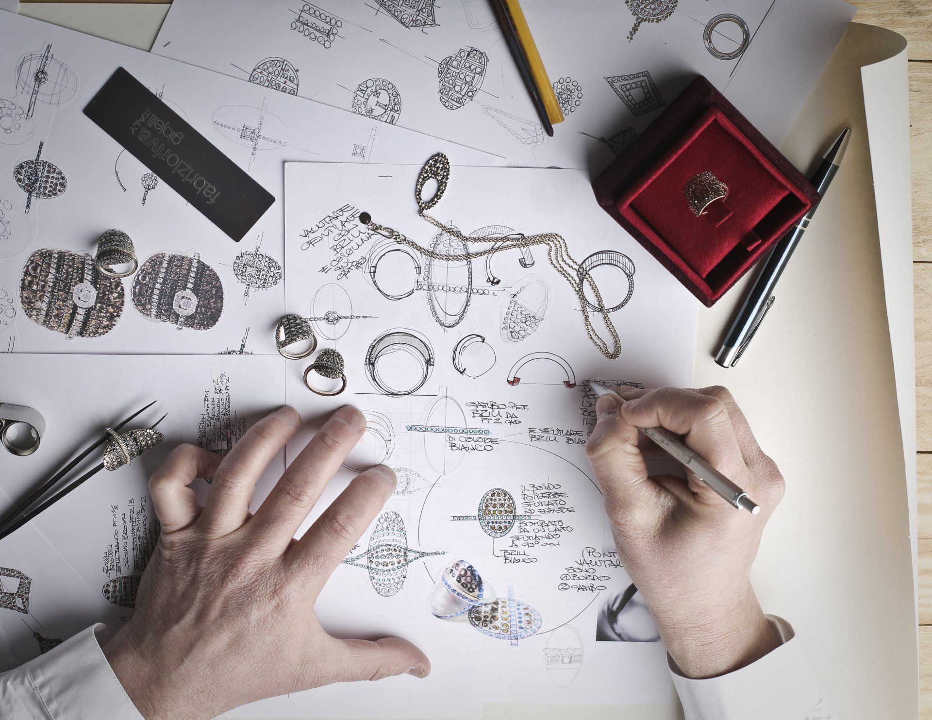 A person is drawing custom jewelry on a piece of paper