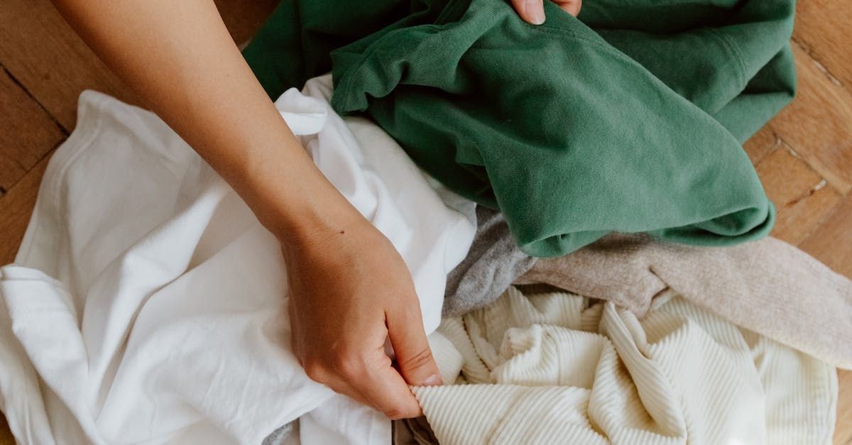A person is putting clothes in a basket on the floor.