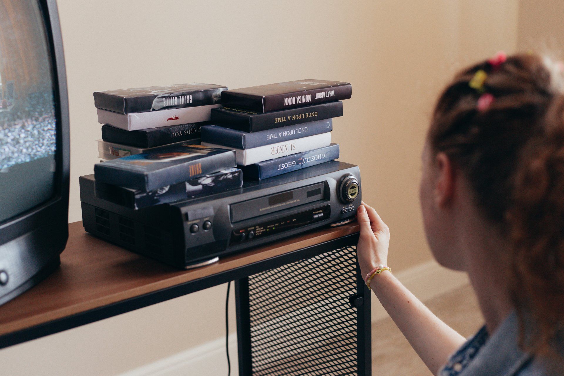 A woman is sitting in front of a stack of dvds on a table.