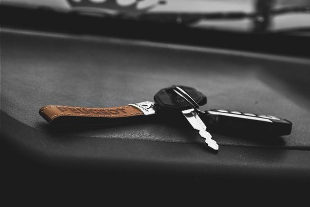Car keys with leather handle on a dark dashboard.