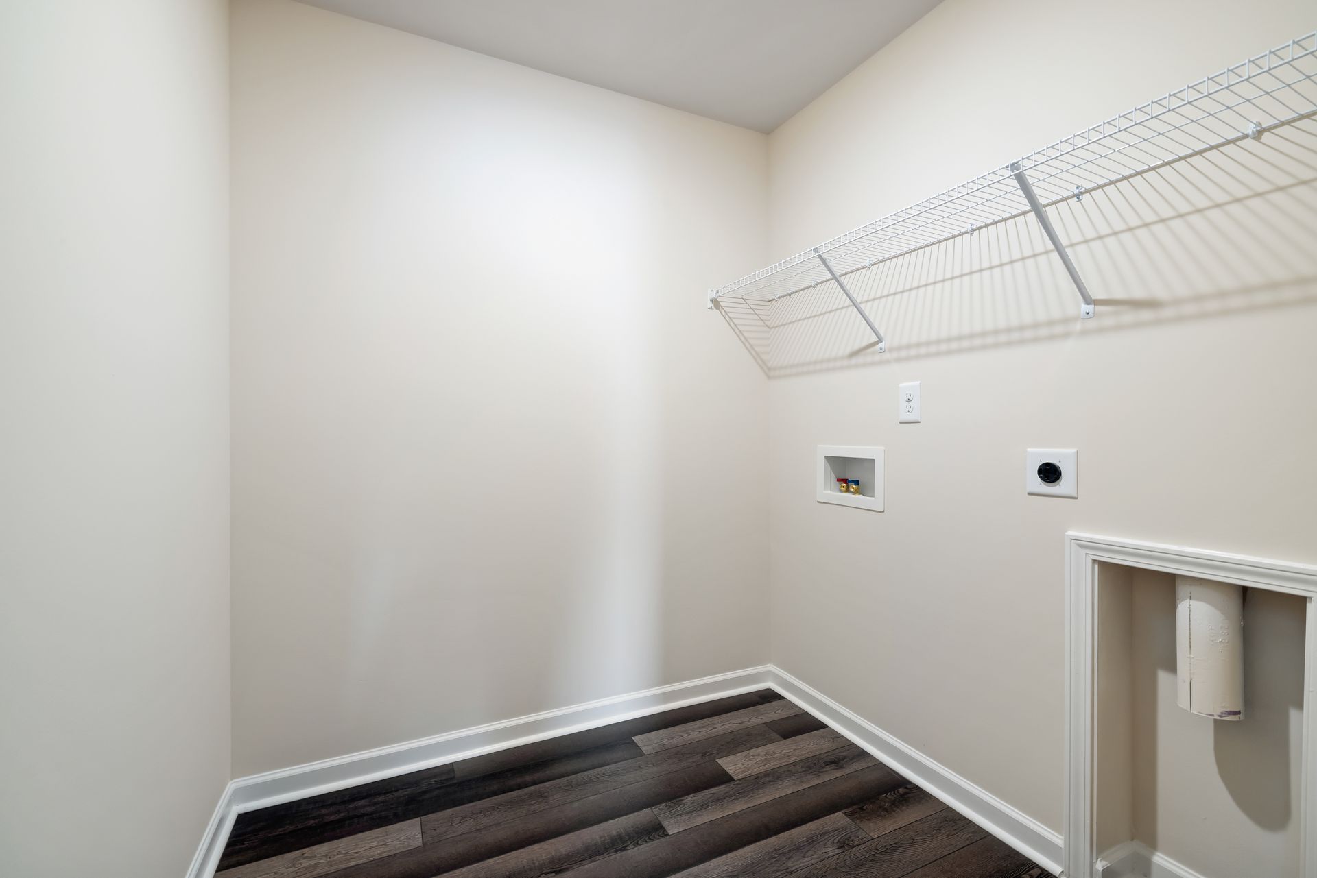 A laundry room with a wooden floor and a washer and dryer.