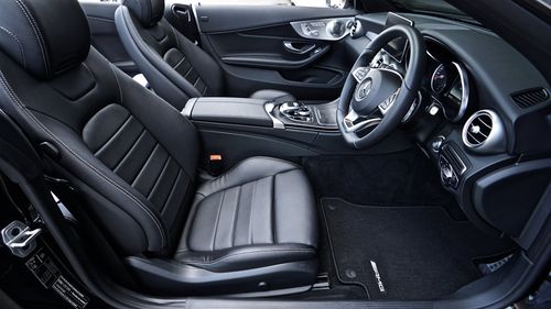 Zwart auto-interieur met lederen stoelen, stuurwiel en dashboard, gezien vanaf de bestuurderskant.