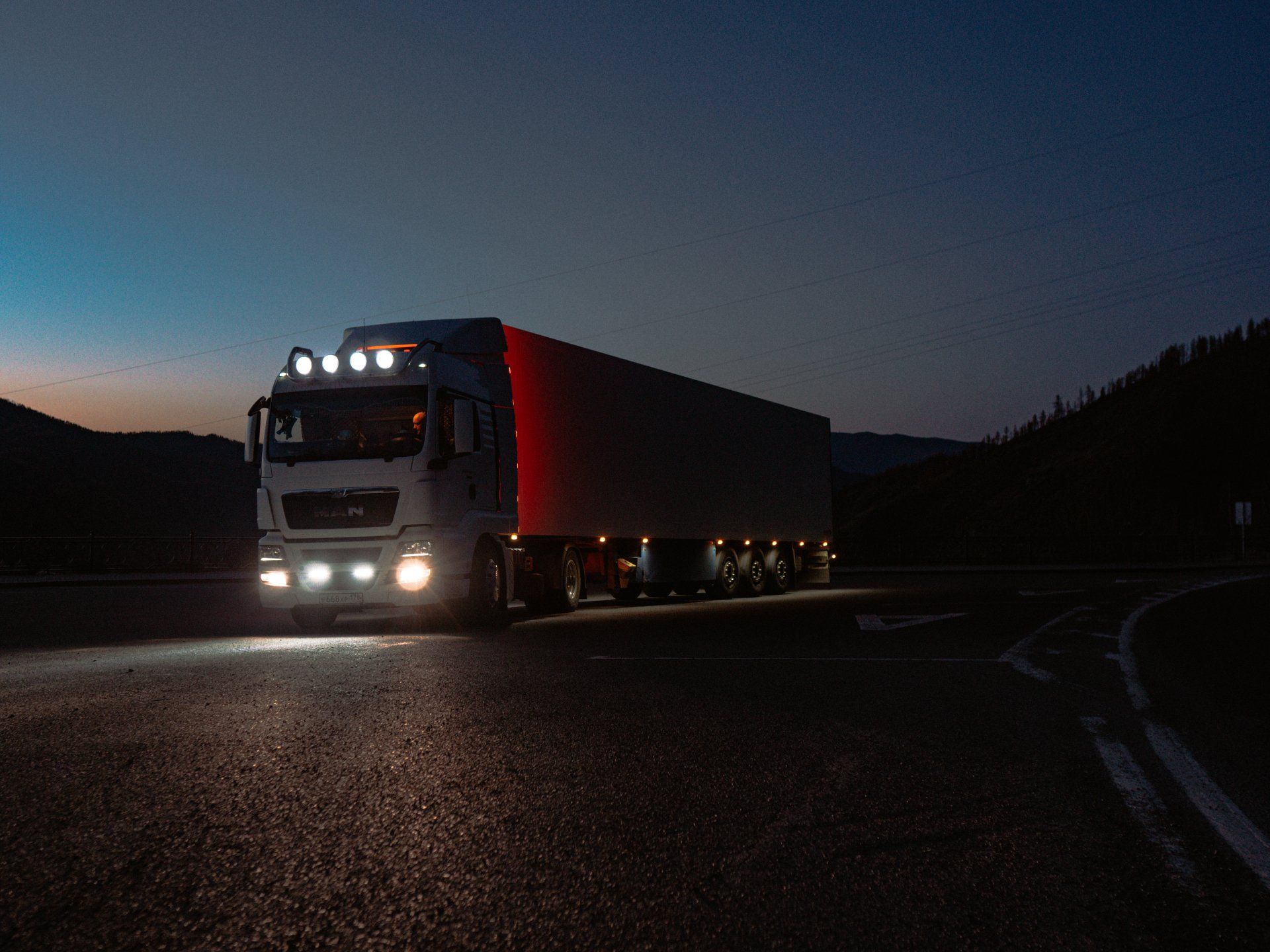 Un semi-remorque roule sur une route la nuit.