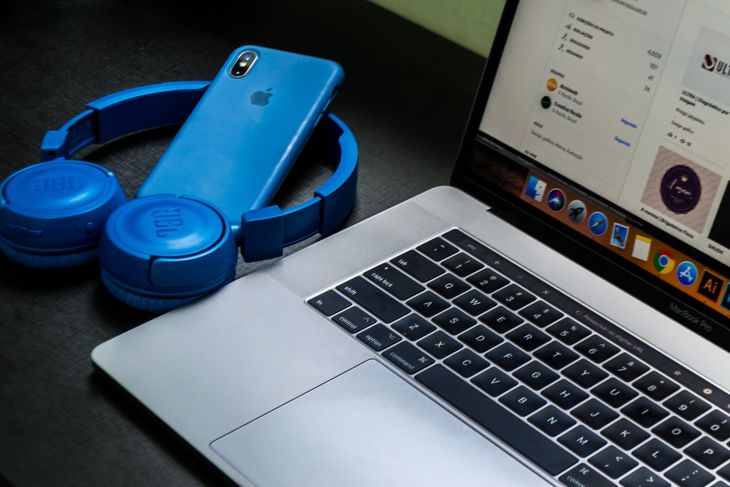 A laptop with headphones and a cell phone on it