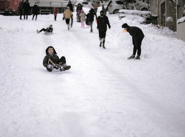 girl smiling in the snow while pulling her beanie