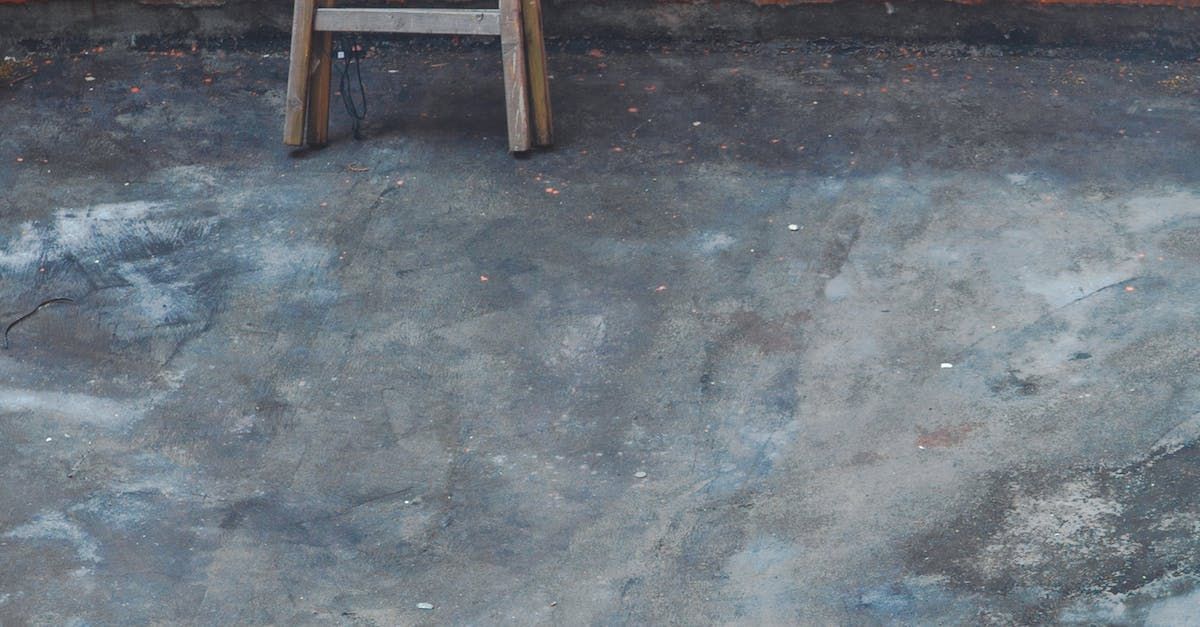 A wooden ladder is sitting on a concrete floor.