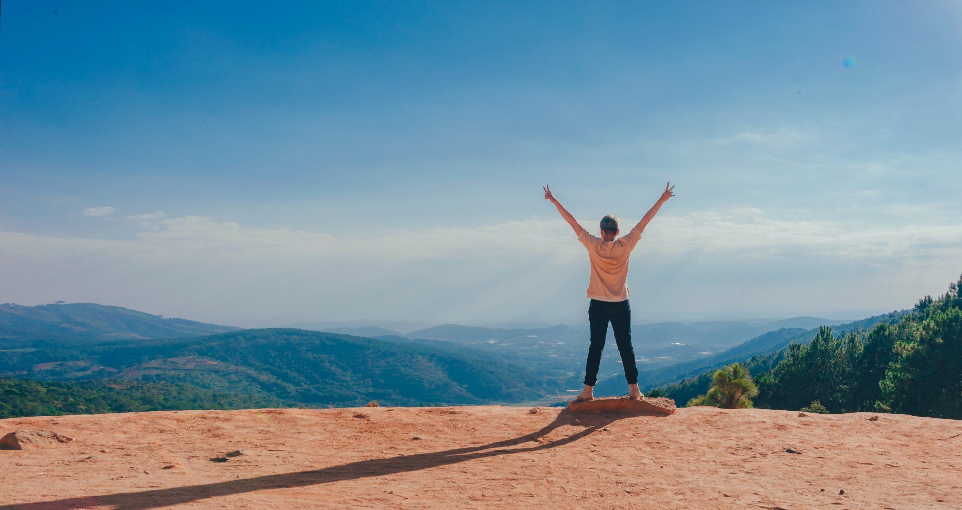 Person standing on a mountain with arms raised in a gesture of freedom