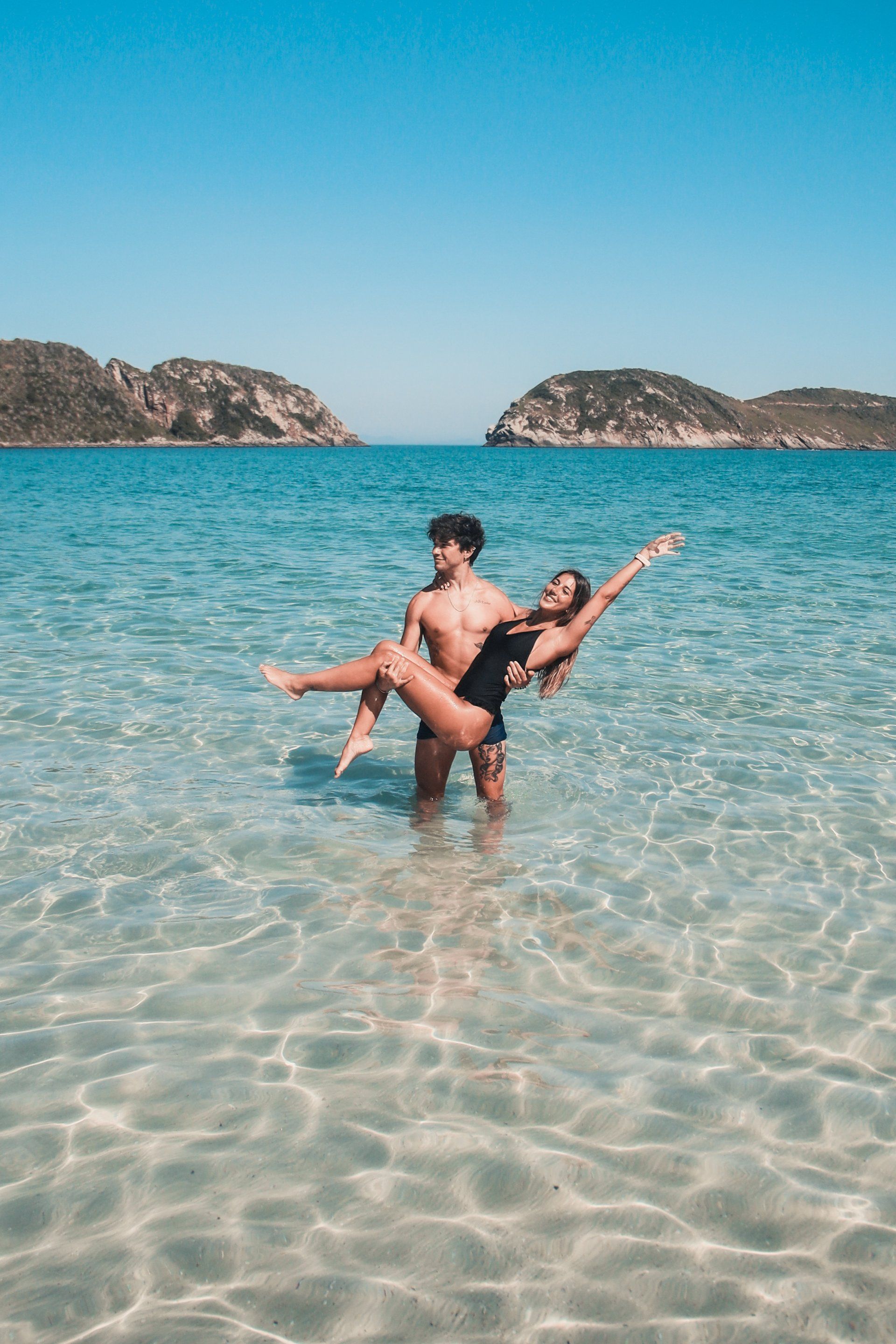 A man is holding a woman in his arms in the ocean.