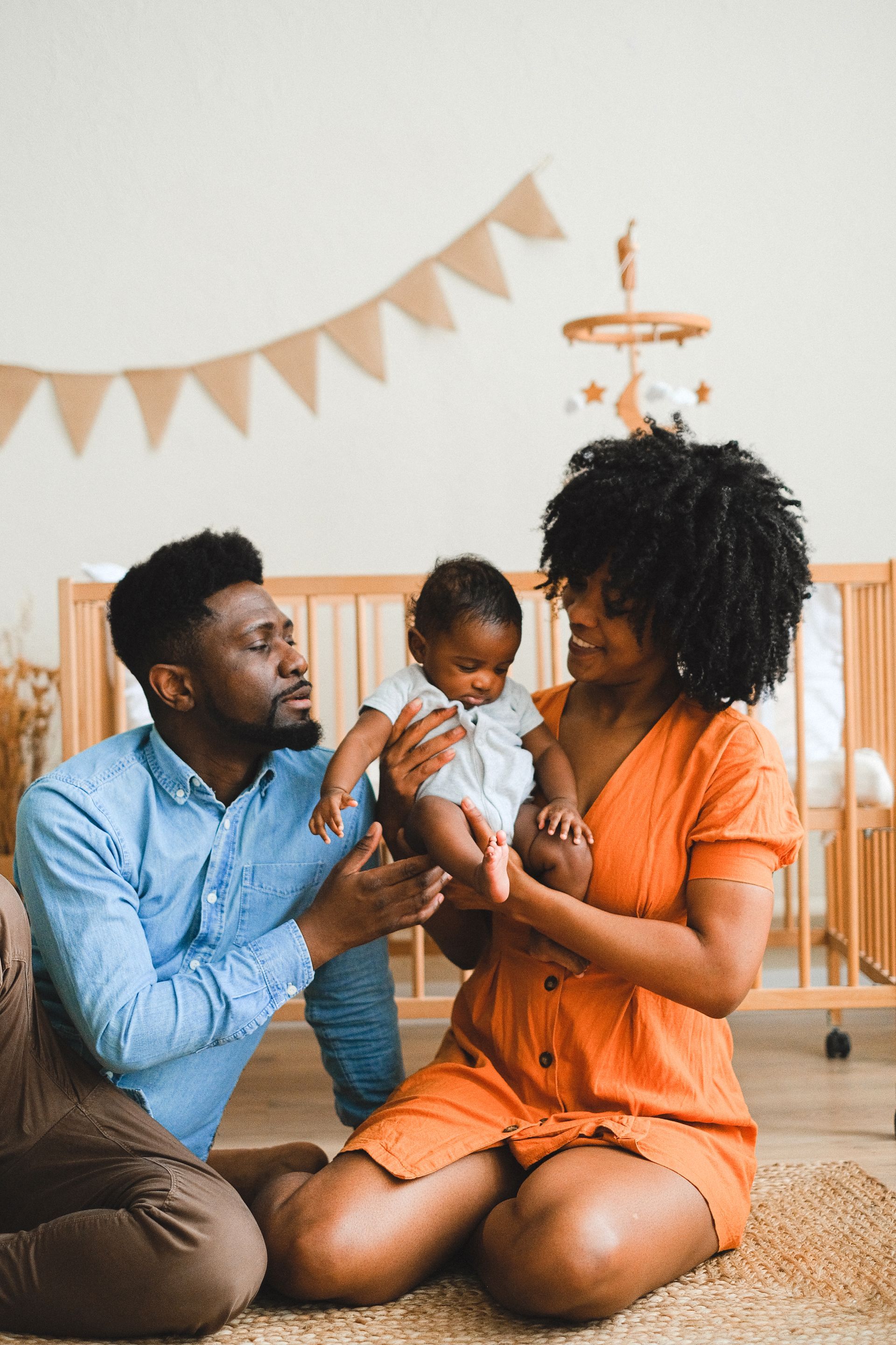 A man and woman are sitting on the floor holding a baby.