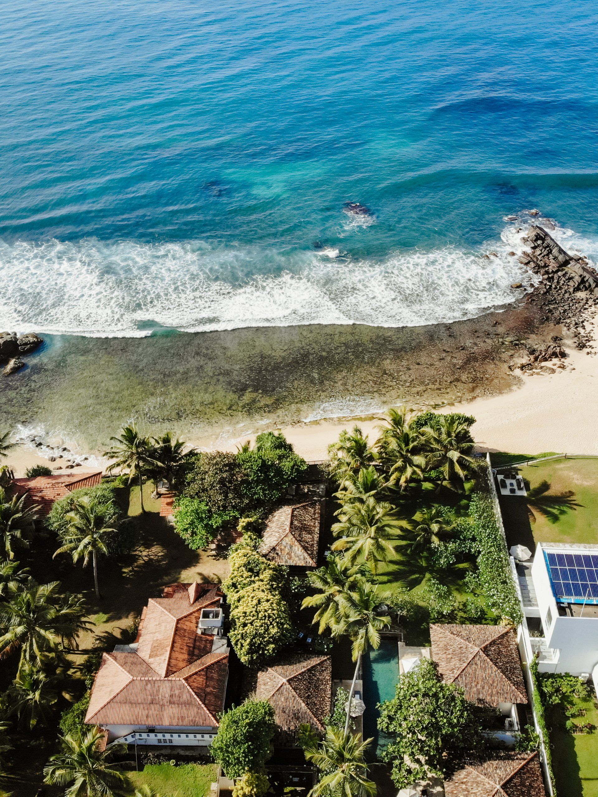 An aerial view of a tropical beach with a house in the foreground.