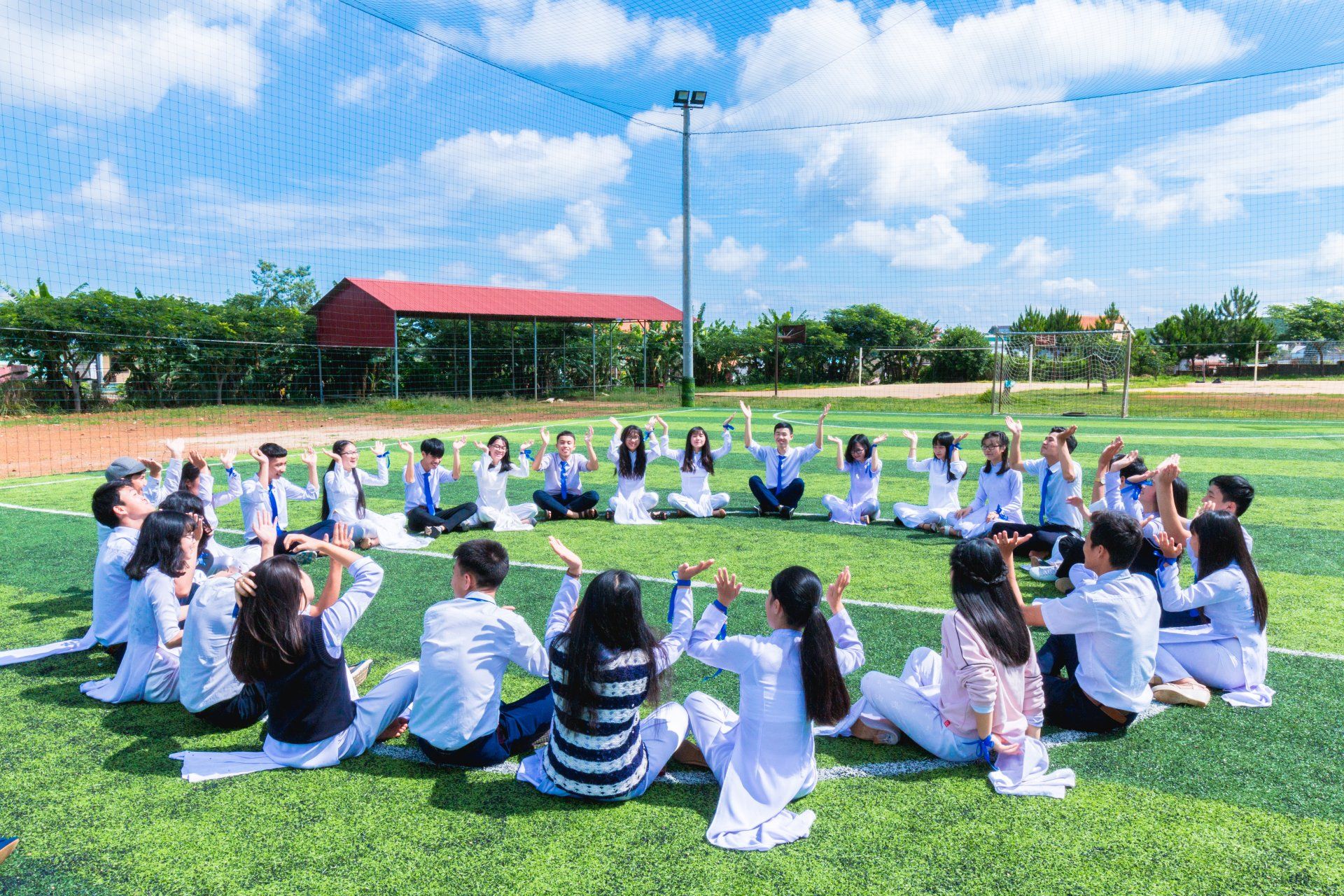 A group of students are sitting in a circle on a field.