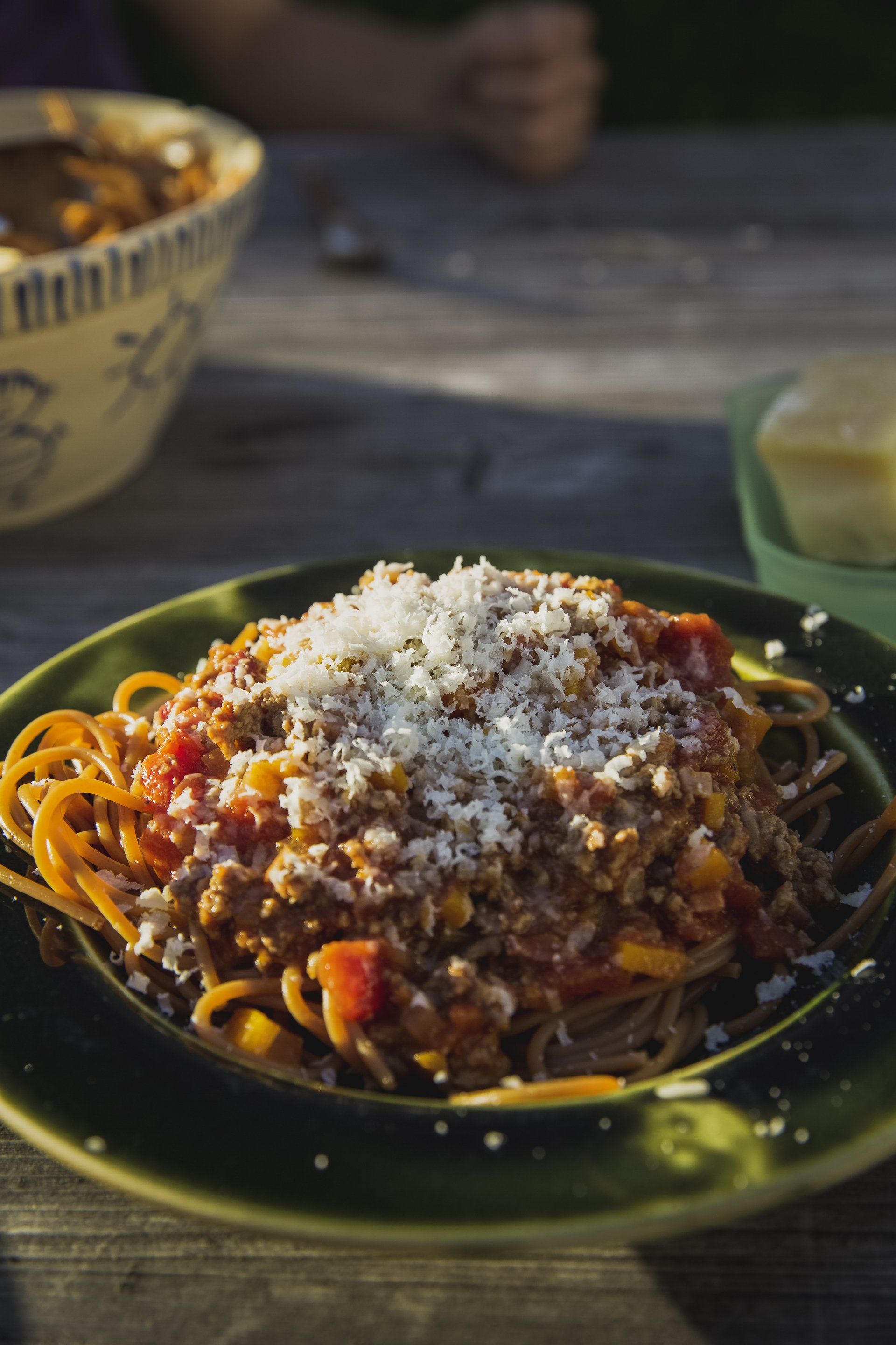 A close up of a plate of spaghetti with meat sauce and cheese on a table.