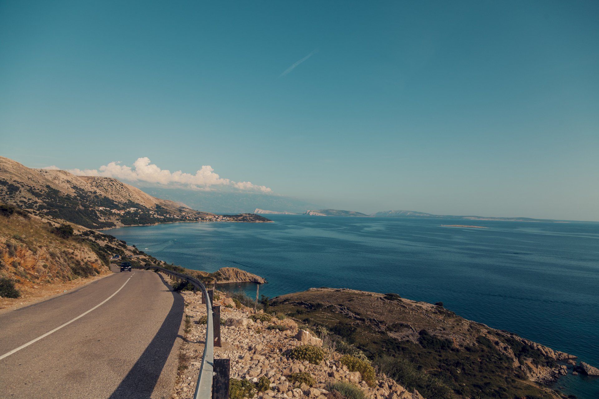 A road going down a hill next to a body of water.