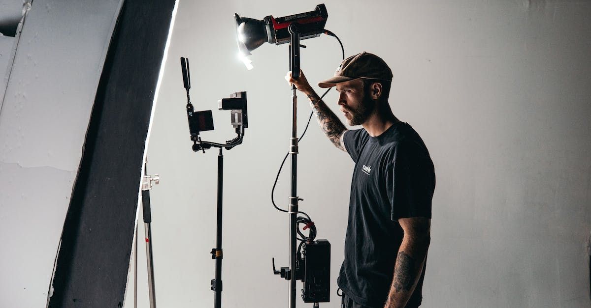 A man is standing in a studio holding a light.