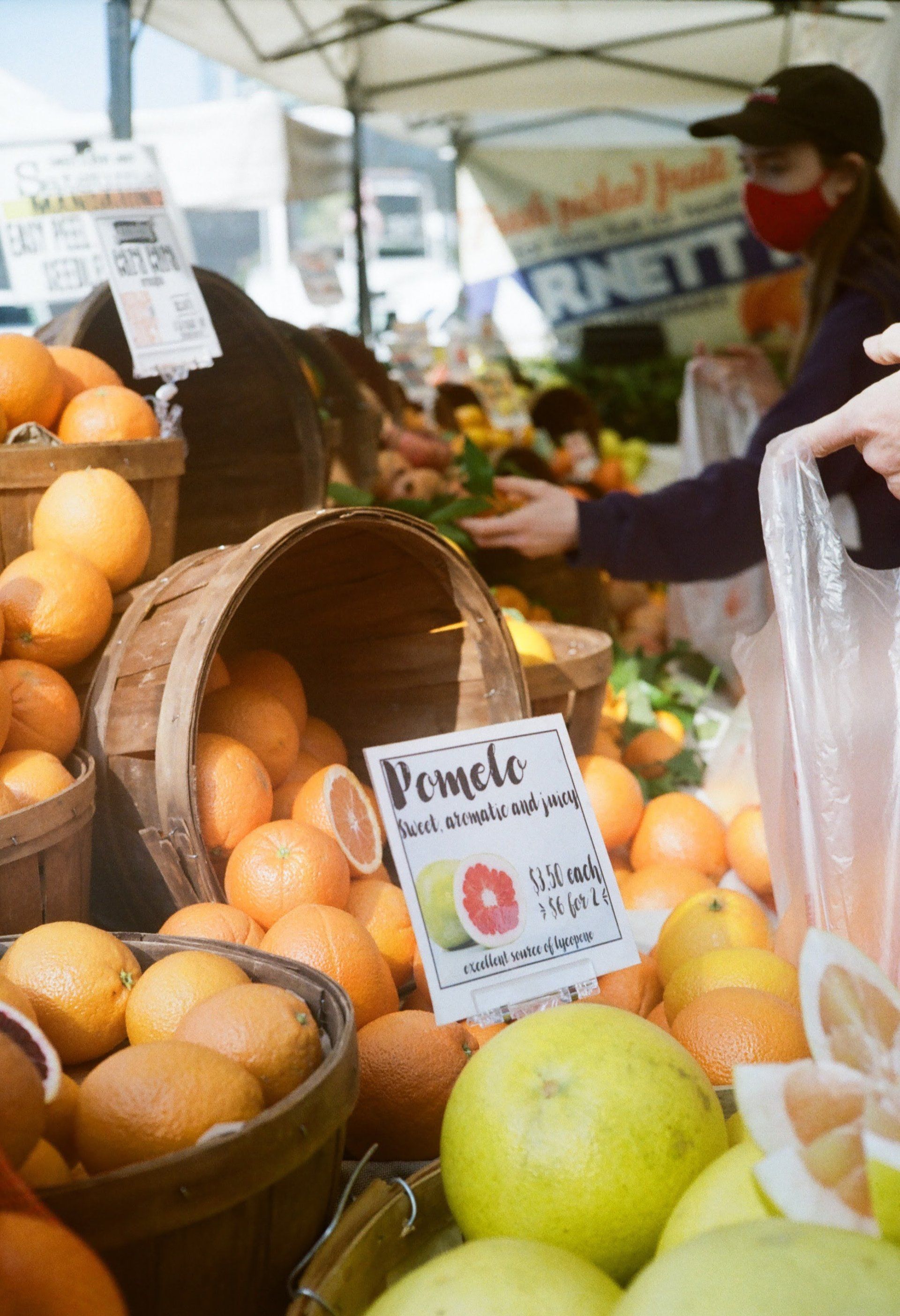 A person is buying oranges at a farmers market.