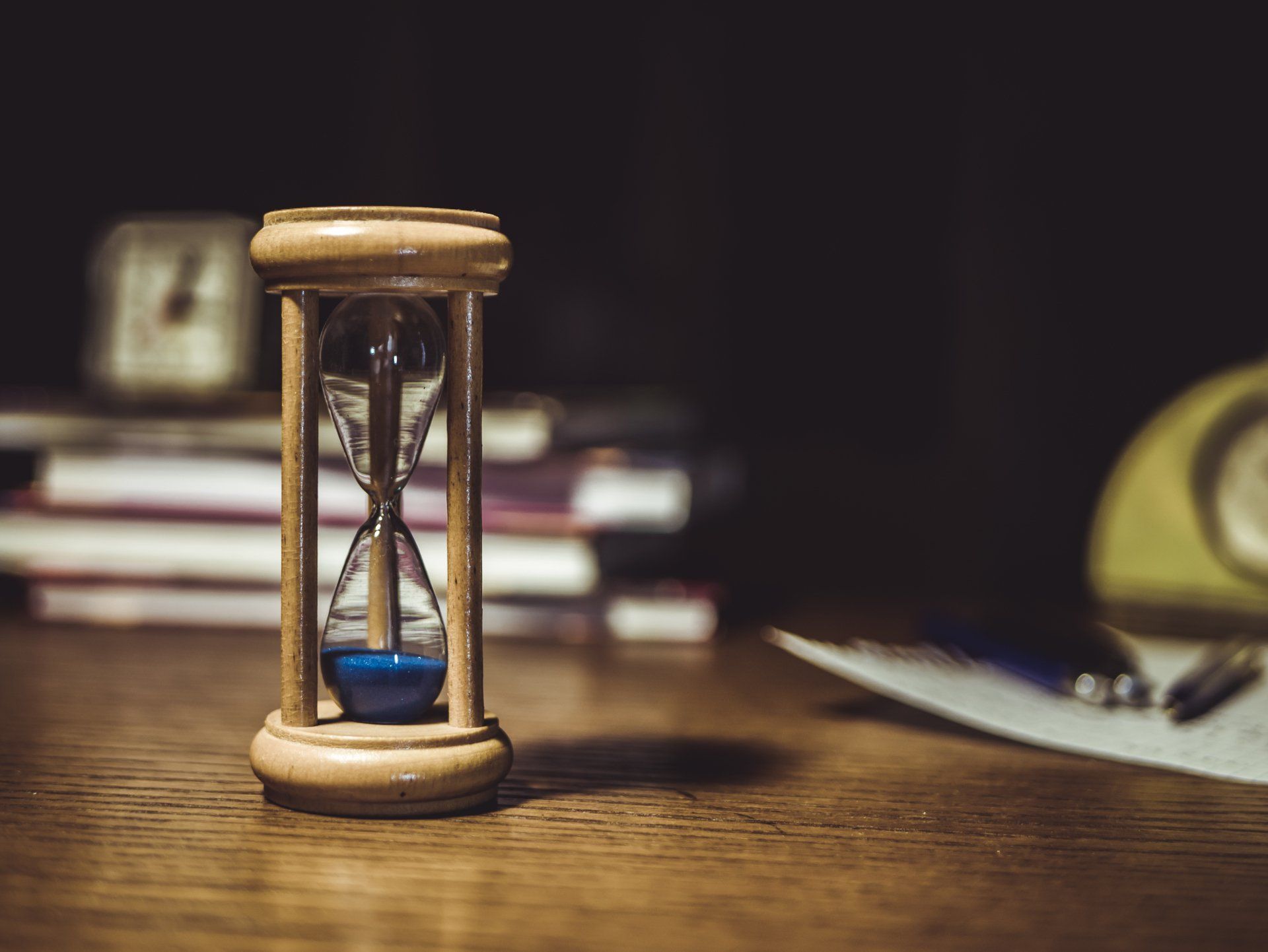 A wooden hourglass is sitting on a wooden table.