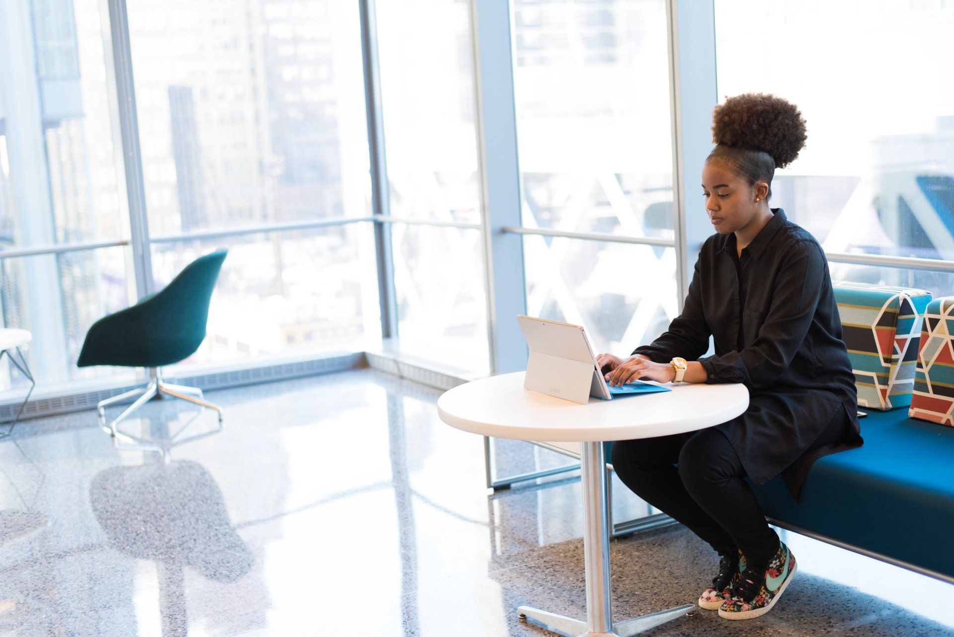 Person working on a laptop at a small table in a bright office lounge