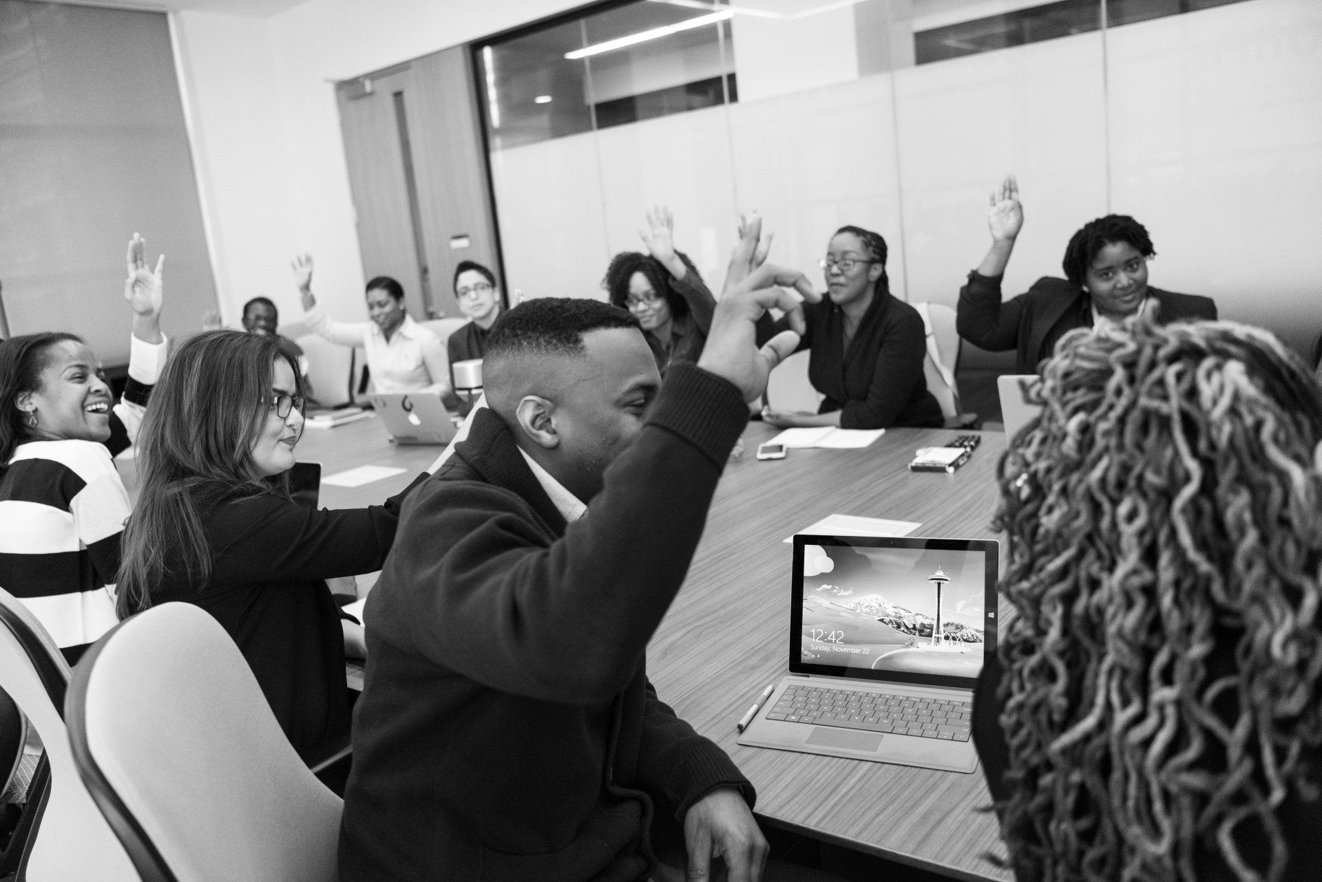 A group of people are sitting around a table with their hands in the air.