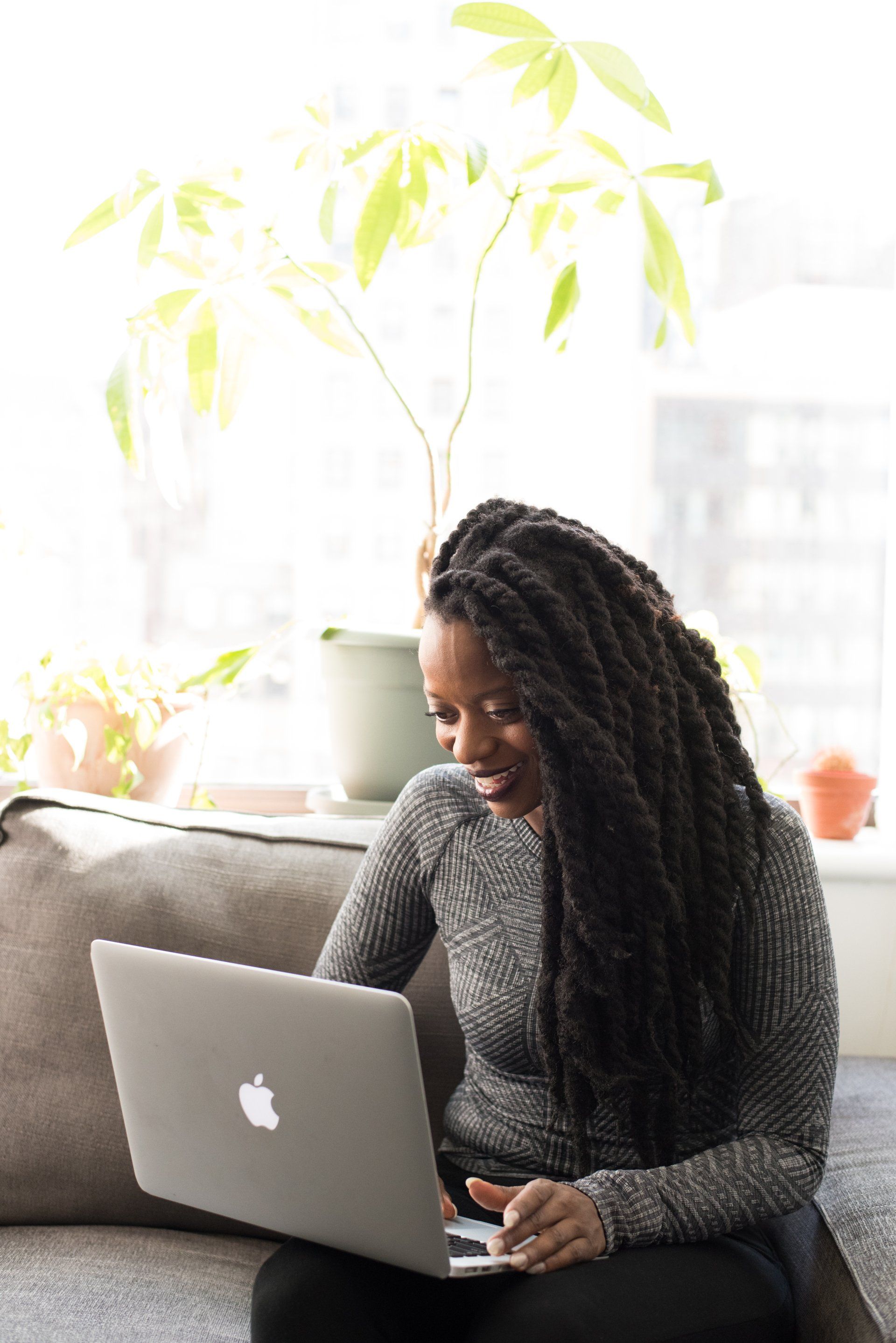 A woman is sitting on a couch using a laptop computer.
