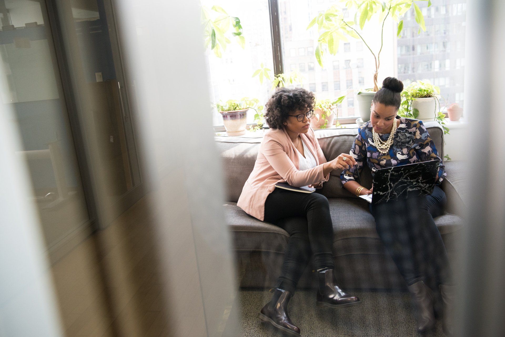 Two women are sitting on a couch talking to each other.