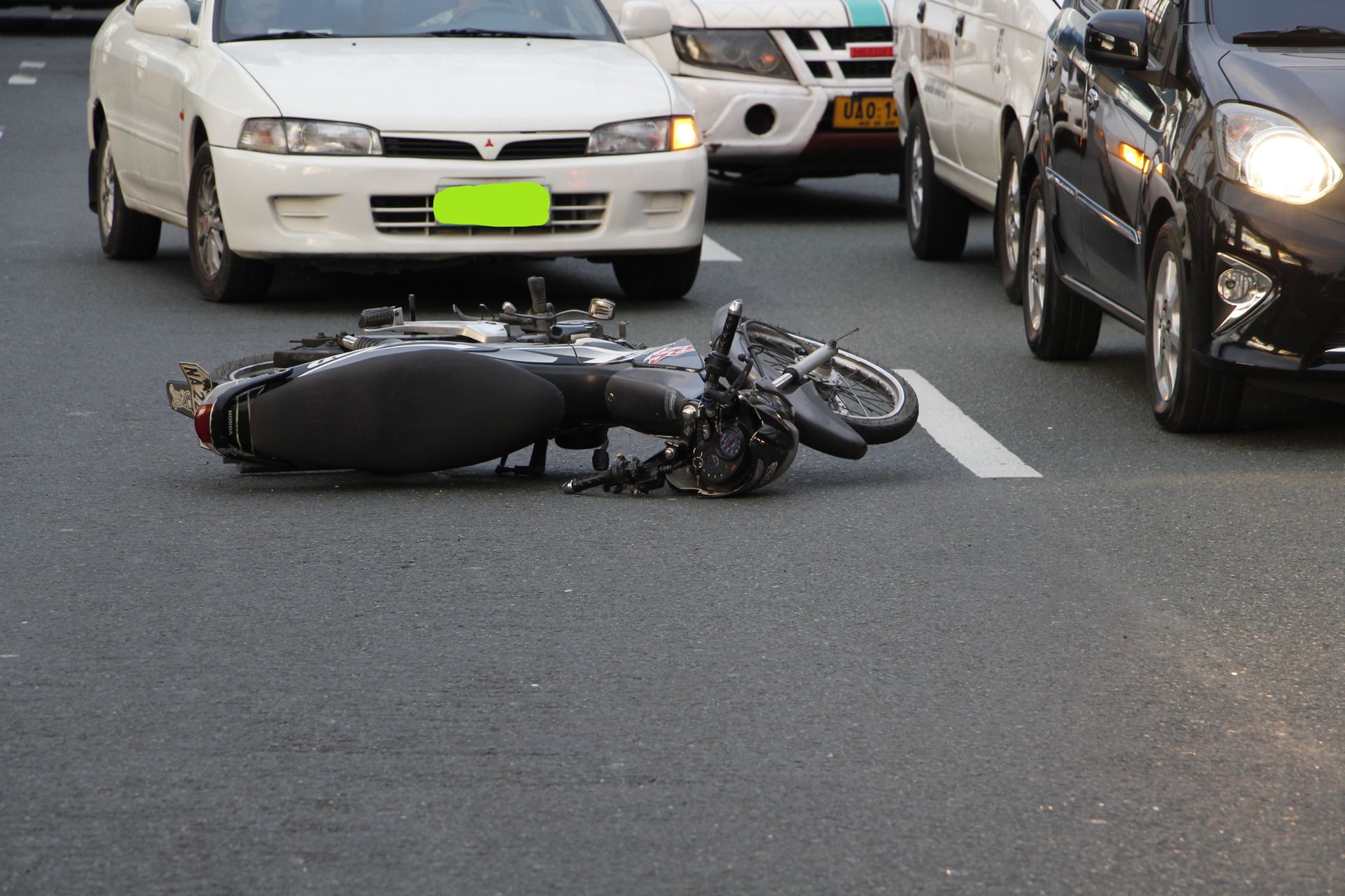 A motorcycle is laying on the side of the road next to a car.