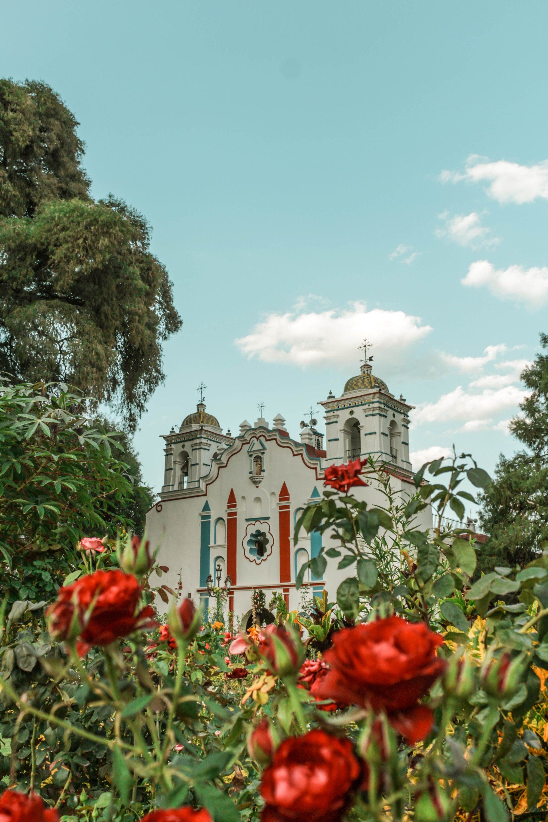 A church with red roses in front of it.