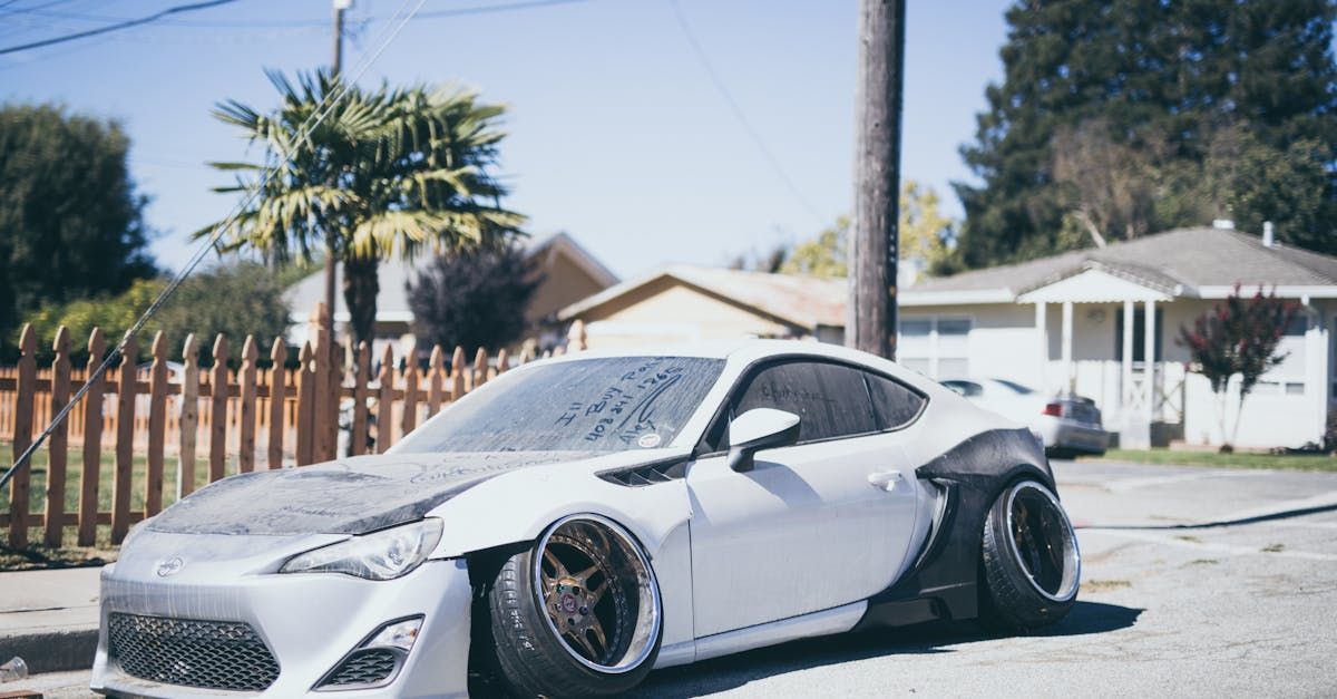 A white sports car is crashed and parked on the side of the road.