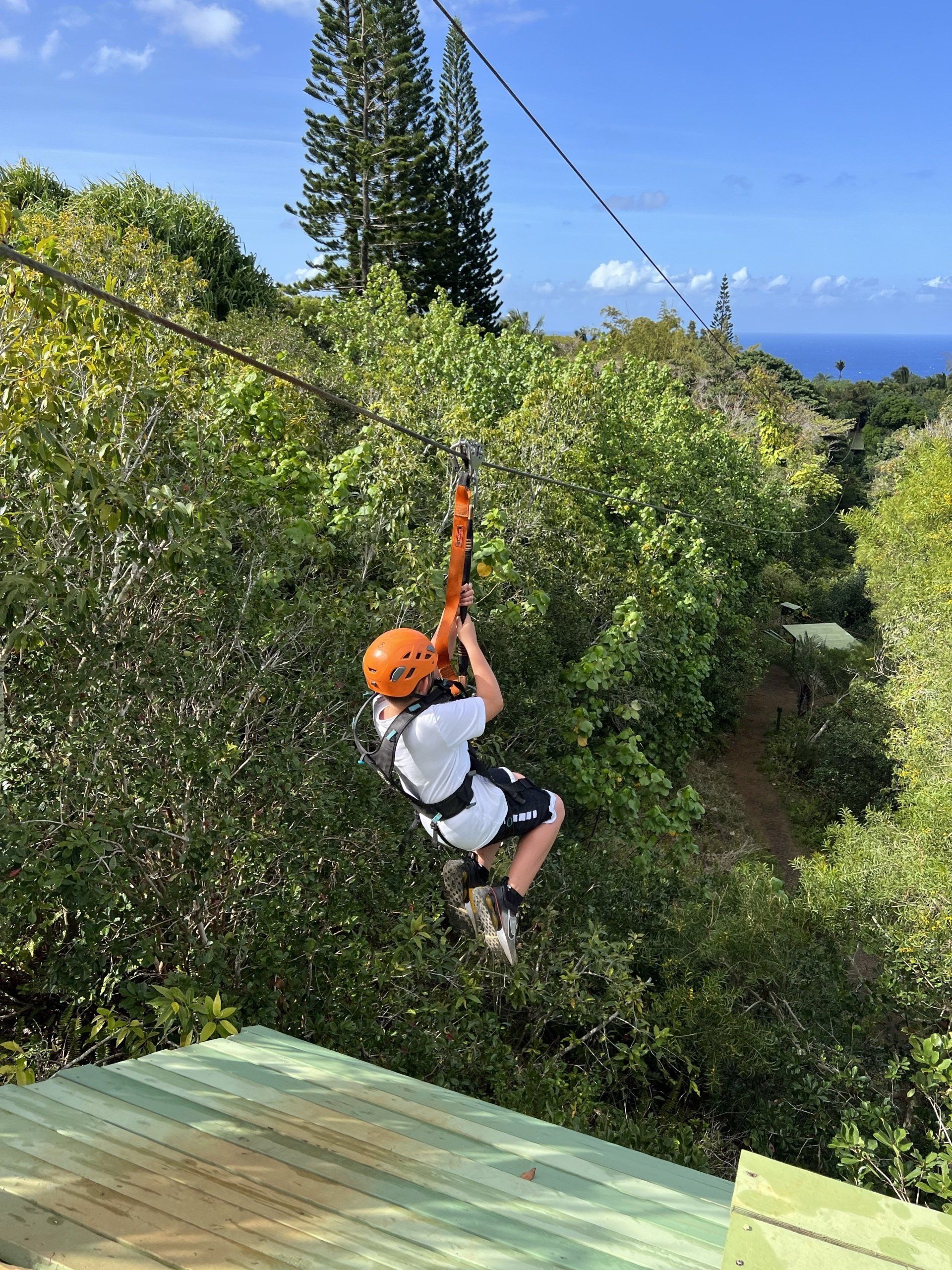 A person is flying through the air on a zip line.