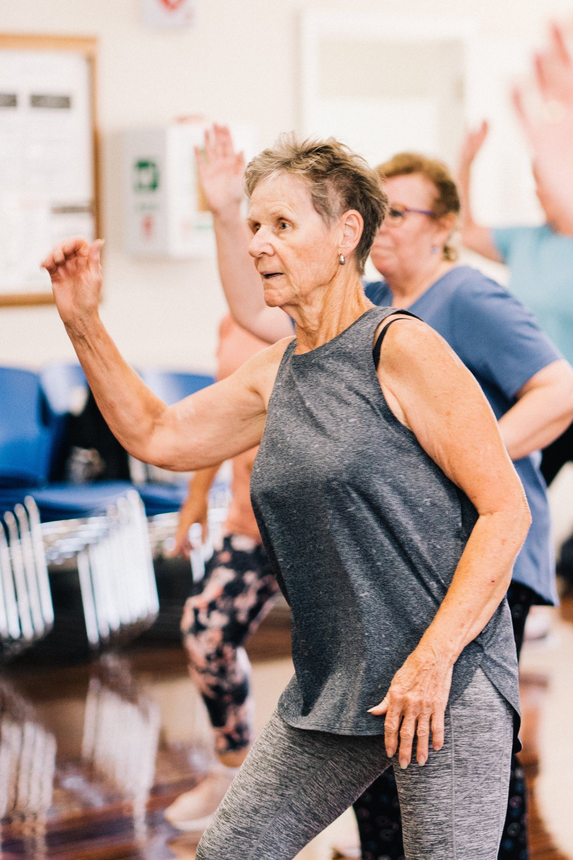 a group of older women are dancing together in a gym .