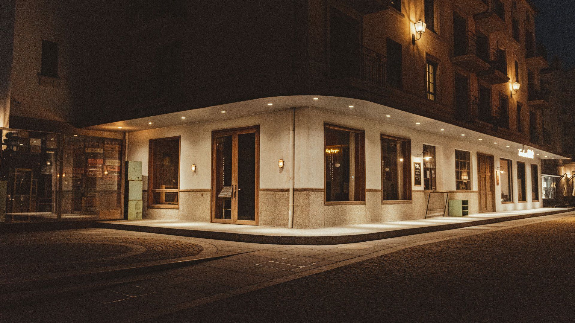 Corner café at night with warm interior lights on a quiet city street corner